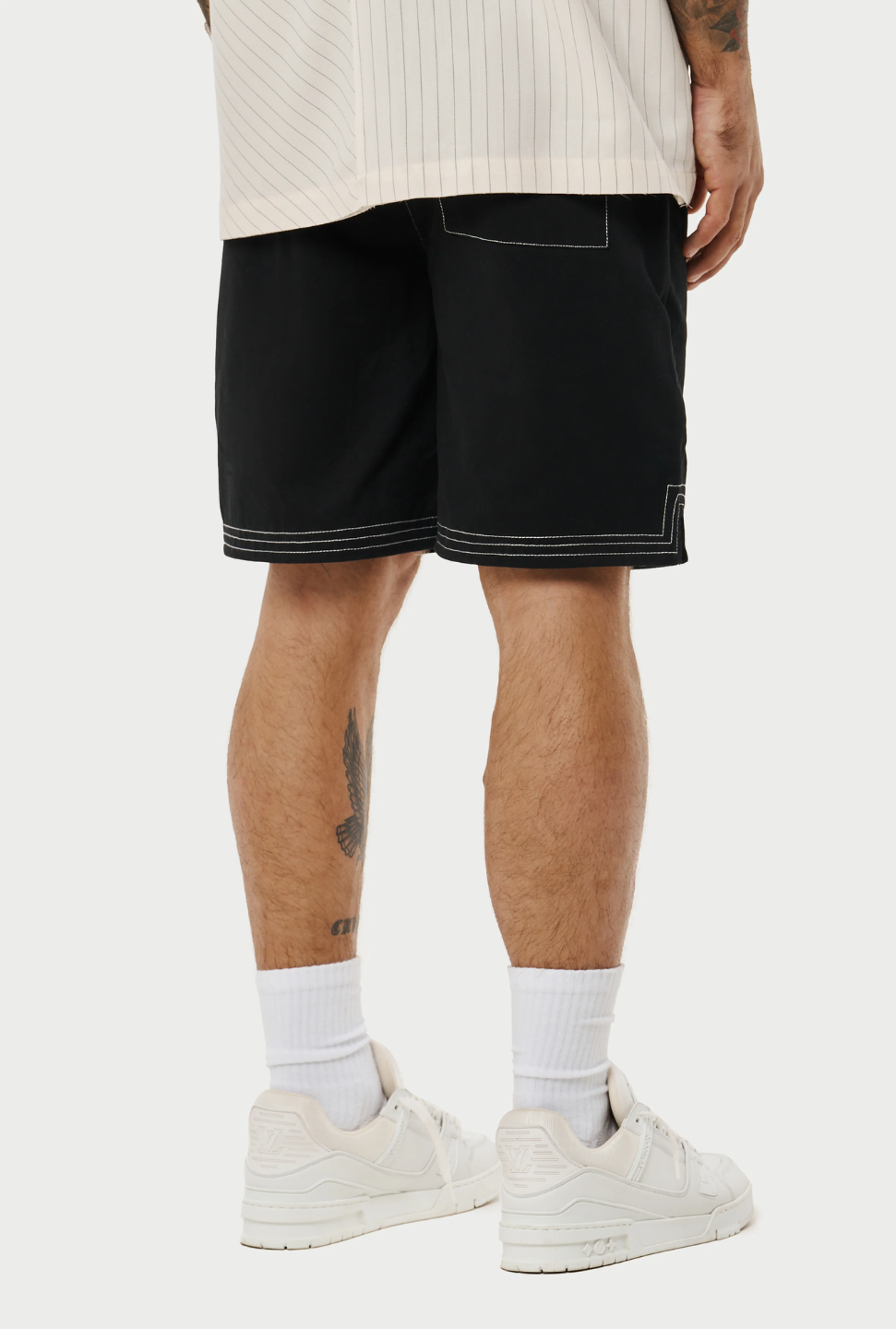 Model wearing a pair of contrast stitch woven shorts, perfect for a relaxed yet stylish look. The shorts are black with a distinctive white contrast stitching that accentuates the seams and pockets, adding a modern touch to the classic design.