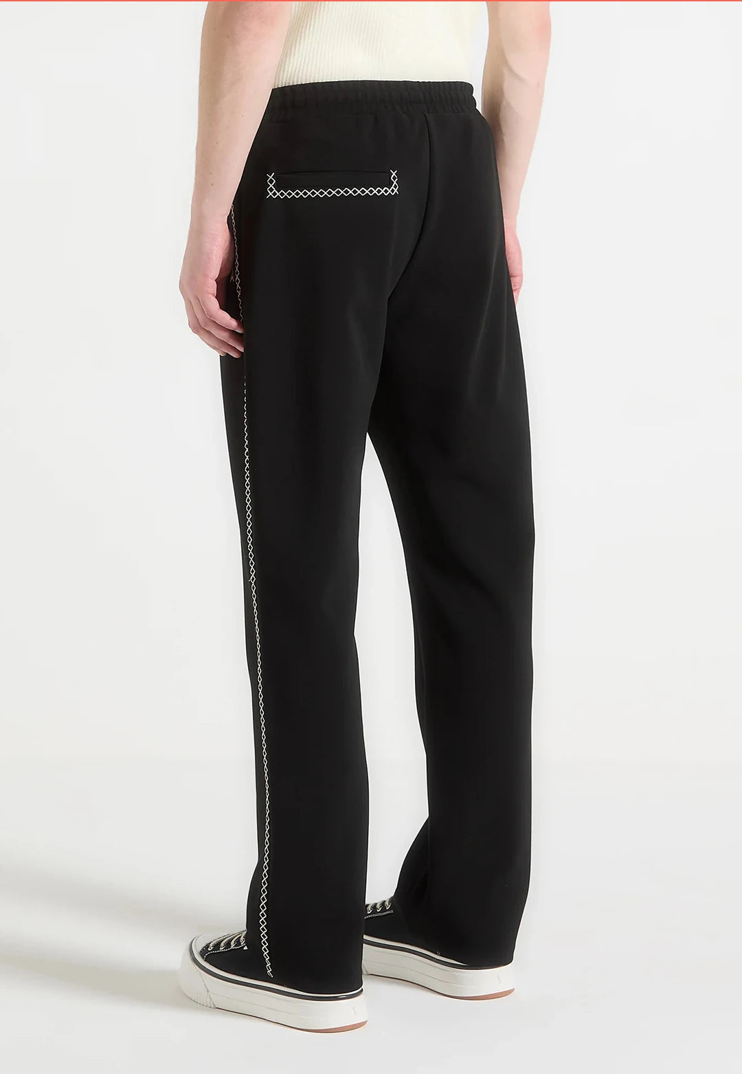 Black pants with a decorative chain detail on a white background