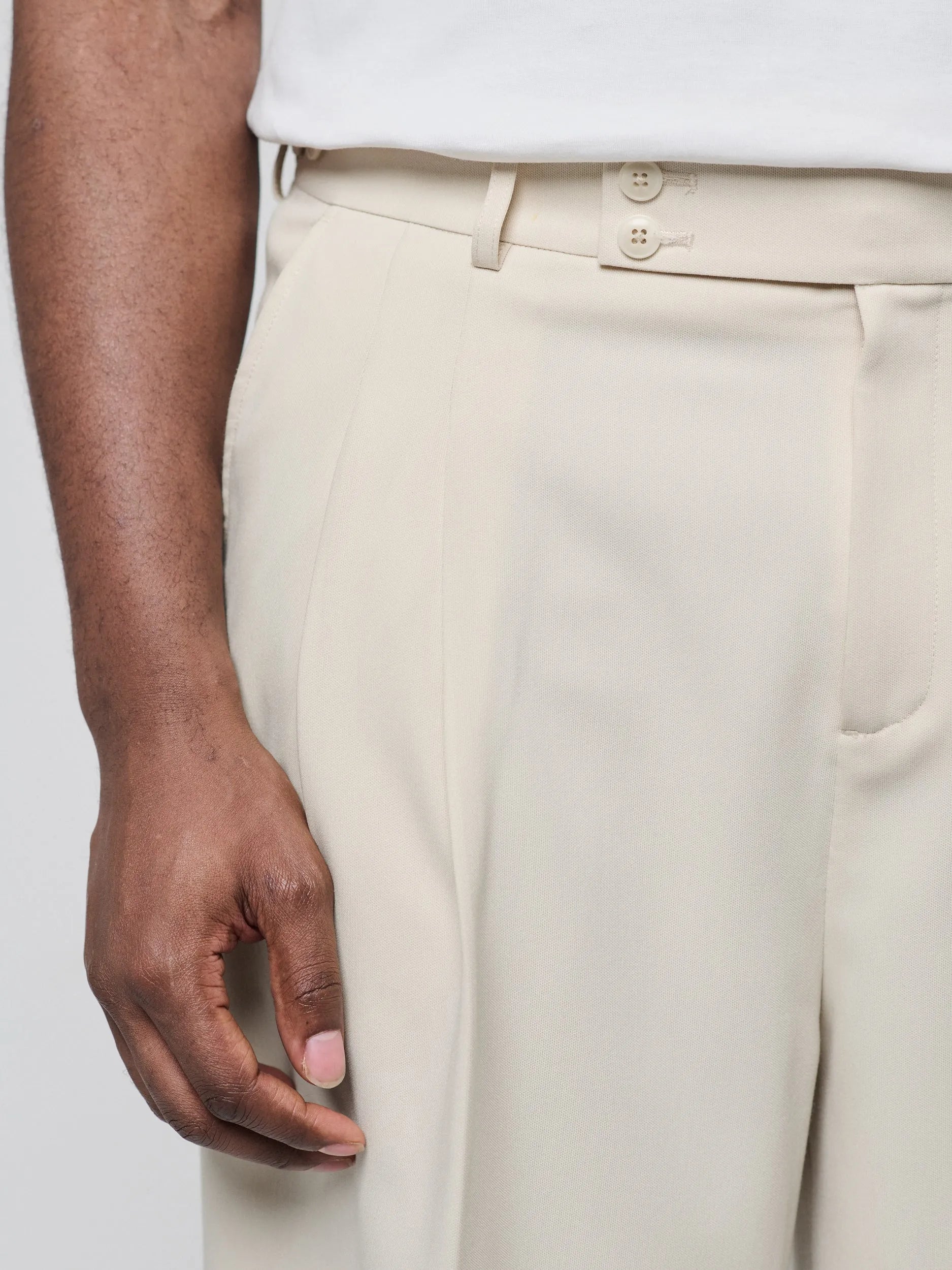 Beige Pants with Double front pleats and adjustable side tabs offer a comfortable, customizable fit, while functional pockets and zip-open hem slits add versatility. Crafted from a smooth cotton blend, they are ideal for refined casual, elevated streetwear, and polished off-duty styling.