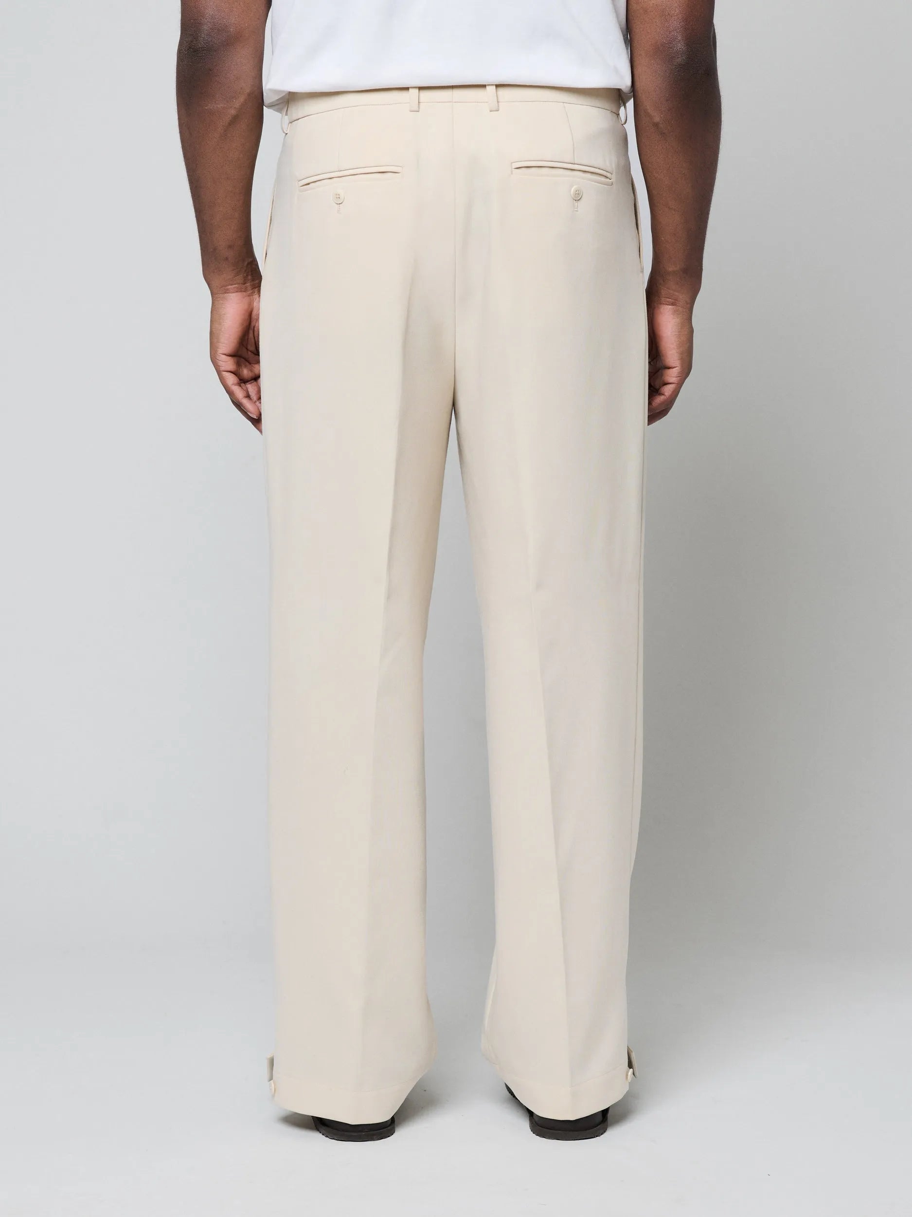 Beige Pants with Double front pleats and adjustable side tabs offer a comfortable, customizable fit, while functional pockets and zip-open hem slits add versatility. Crafted from a smooth cotton blend, they are ideal for refined casual, elevated streetwear, and polished off-duty styling.