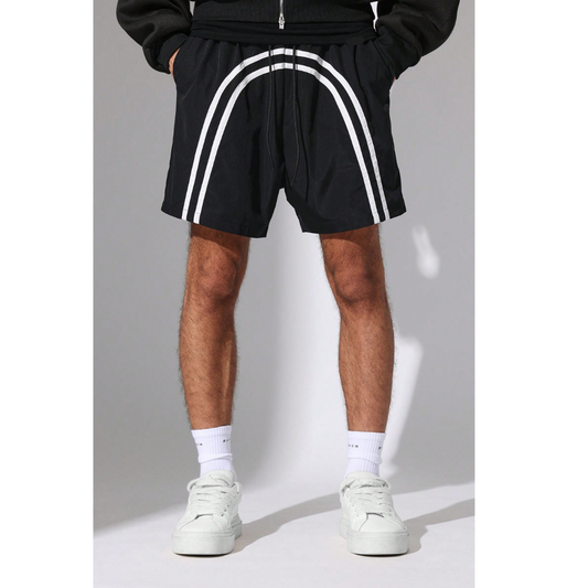 Person wearing black shorts with white stripes, white socks, and white sneakers on a grey background