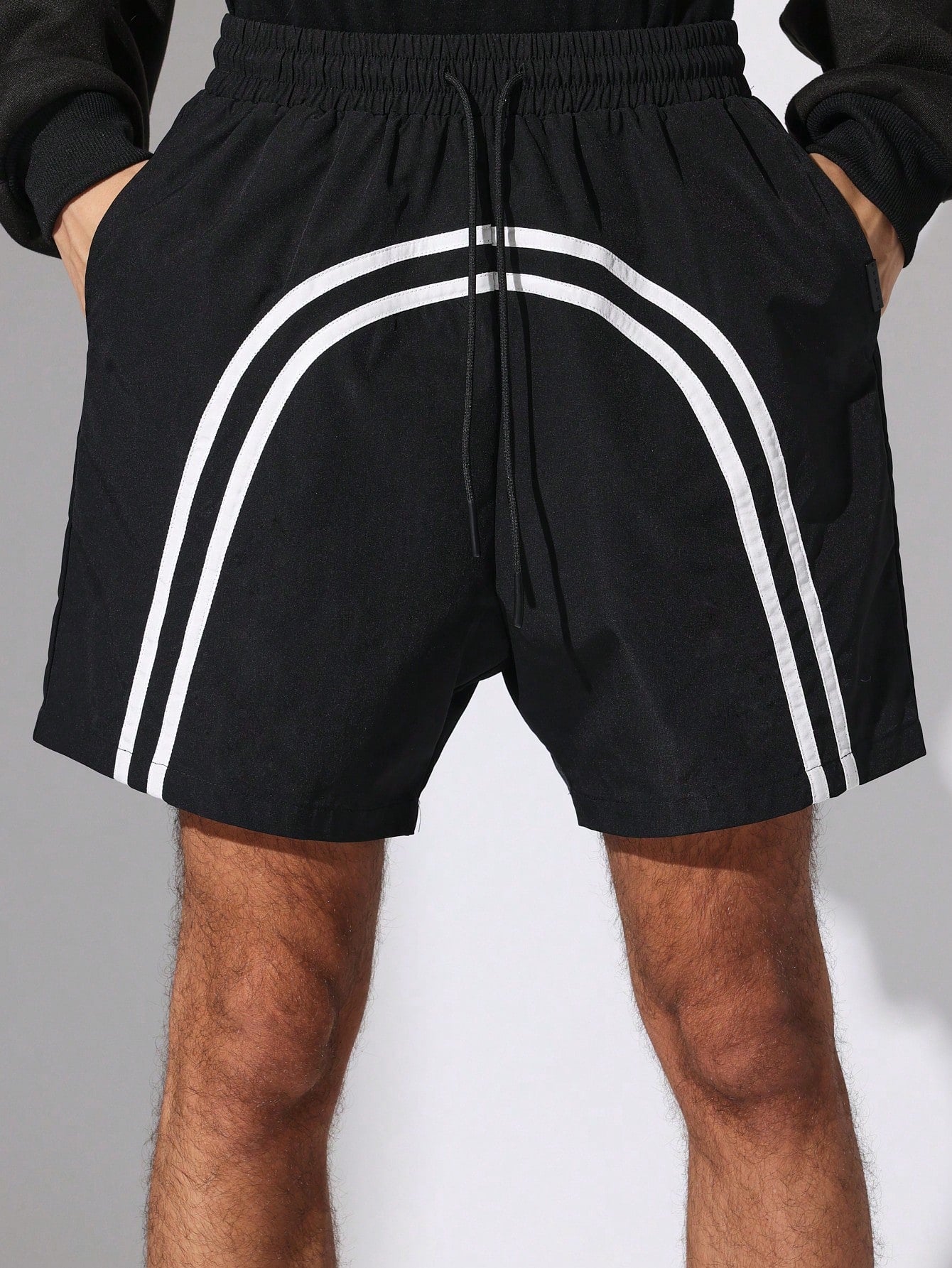 Black shorts with white stripes on a grey background