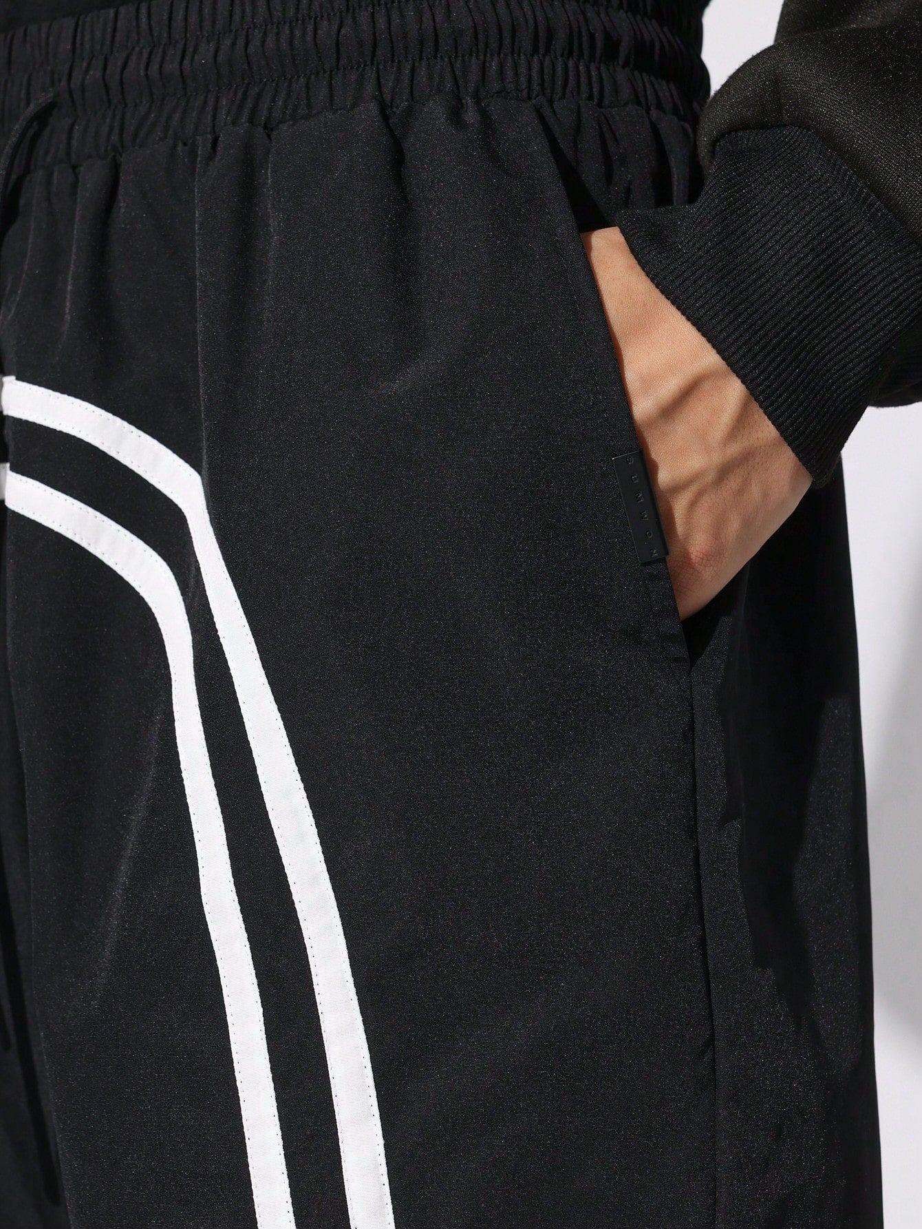 Black shorts with white stripes on a plain background