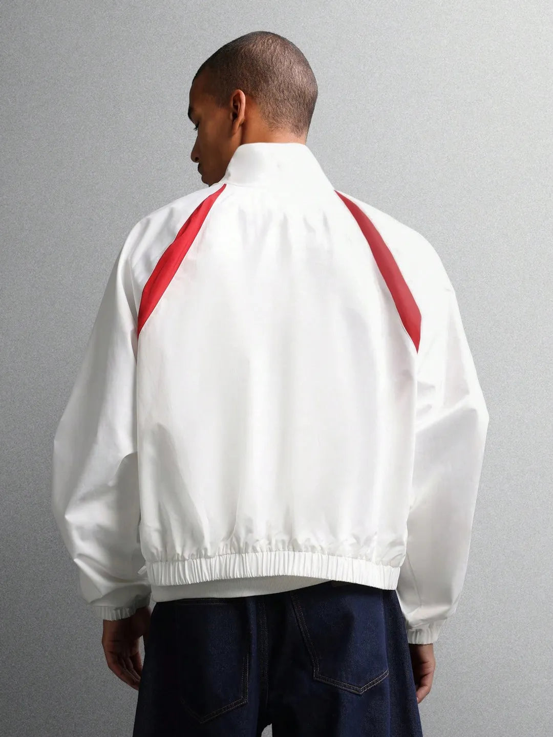 Person wearing a white jacket with red accents on a gray background