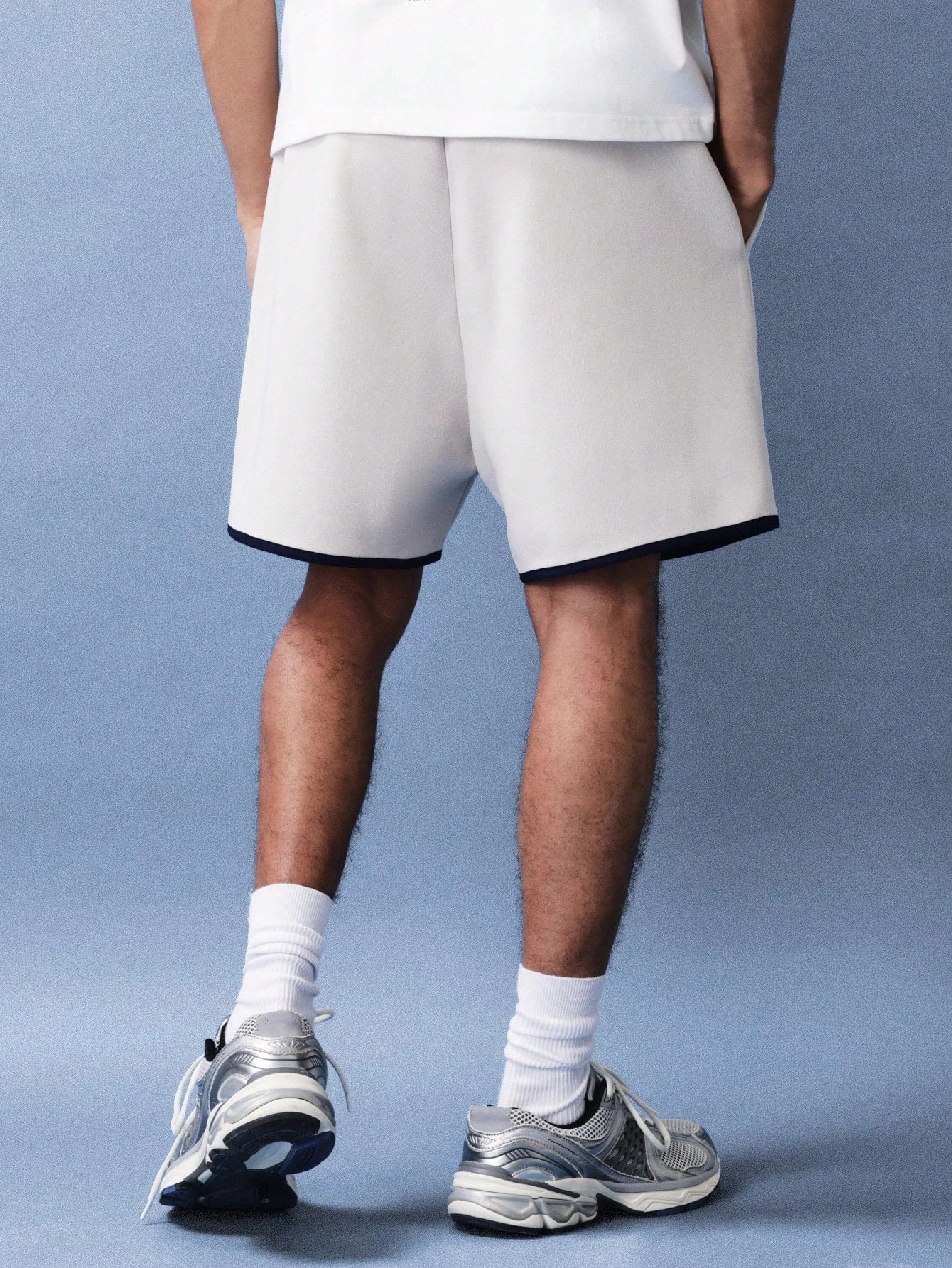 Person wearing white shorts and sneakers on a blue background