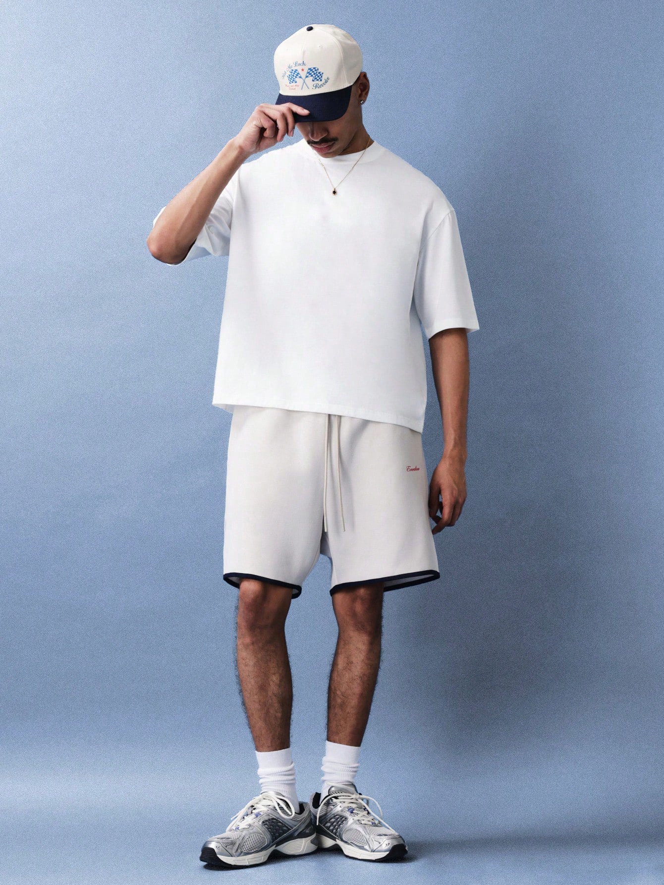 Person wearing a white t-shirt, shorts, and sneakers against a light blue background