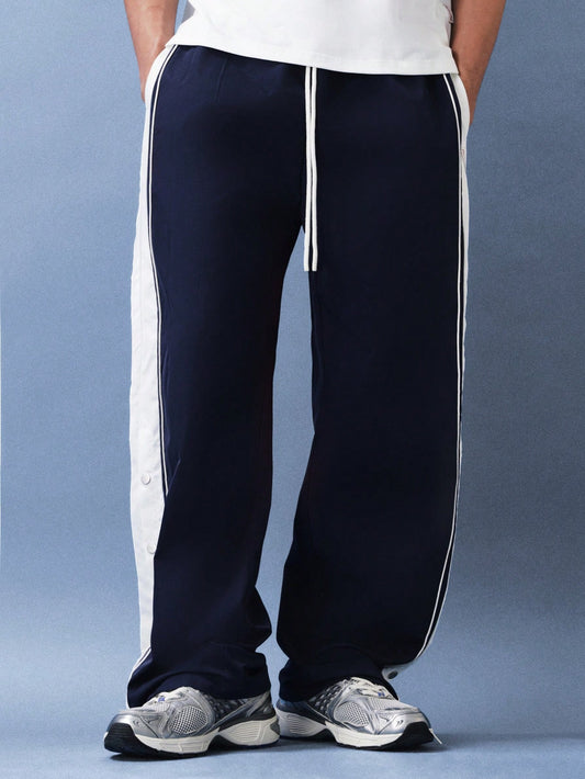 Navy track pants with white stripes worn by a person on a blue background