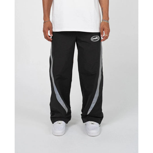 Black track pants with gray stripes worn by a person on a white background