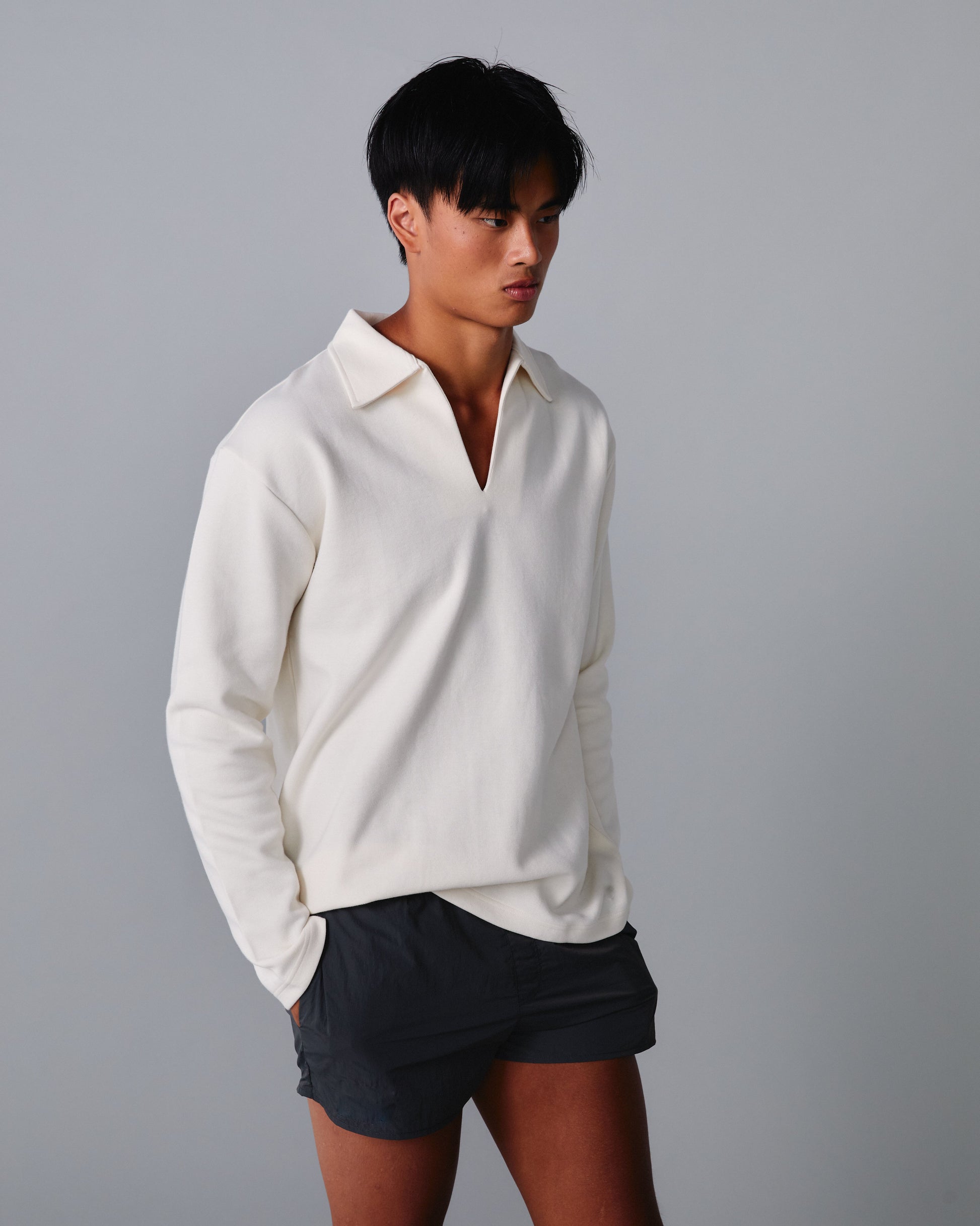 Person wearing a white shirt and black shorts against a grey background