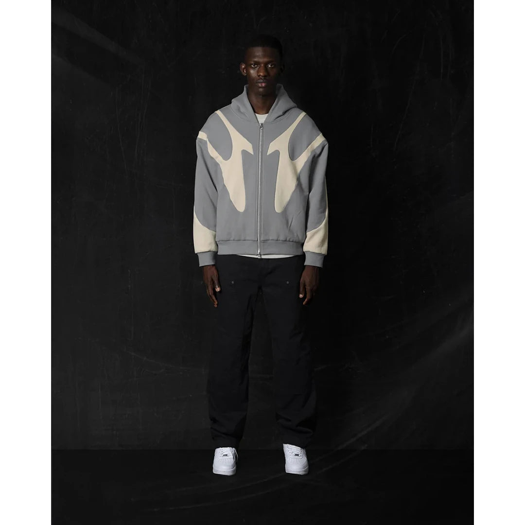 Person wearing a gray and beige hoodie with flame design on a black background