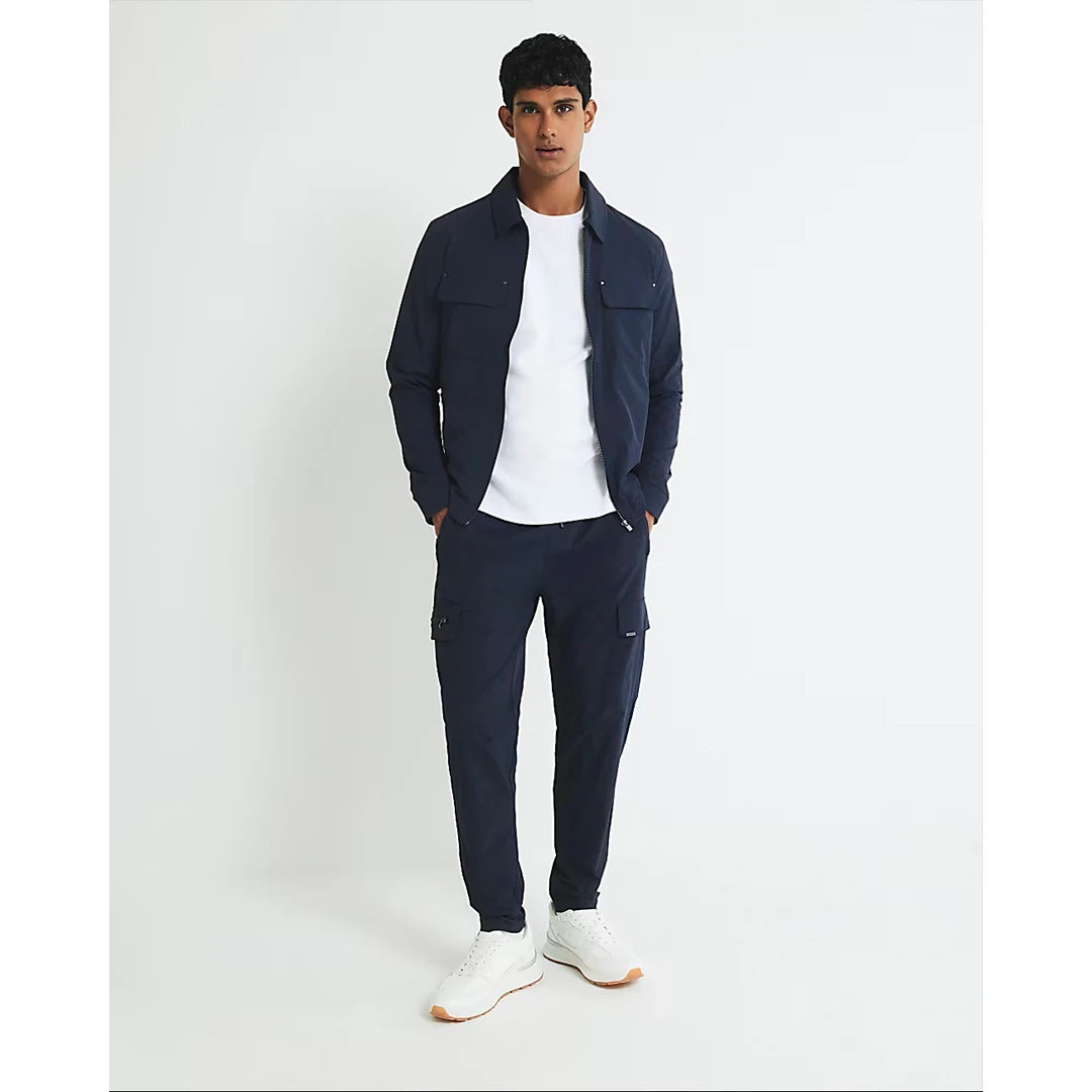 Man wearing a navy jacket and pants with a white shirt on a white background