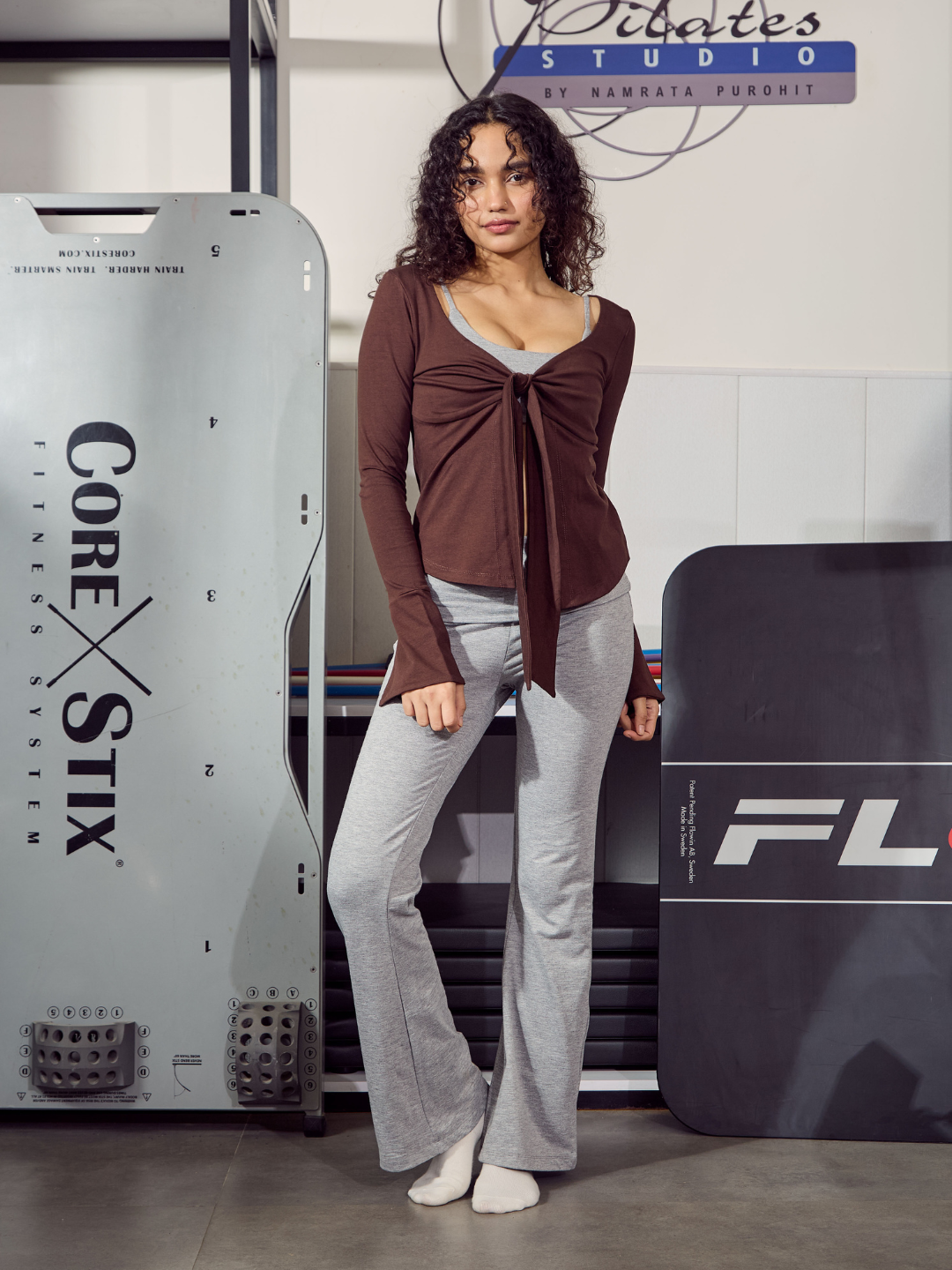 Woman standing next to exercise equipment with 'Core Stix' and 'FL' branding in the background.
