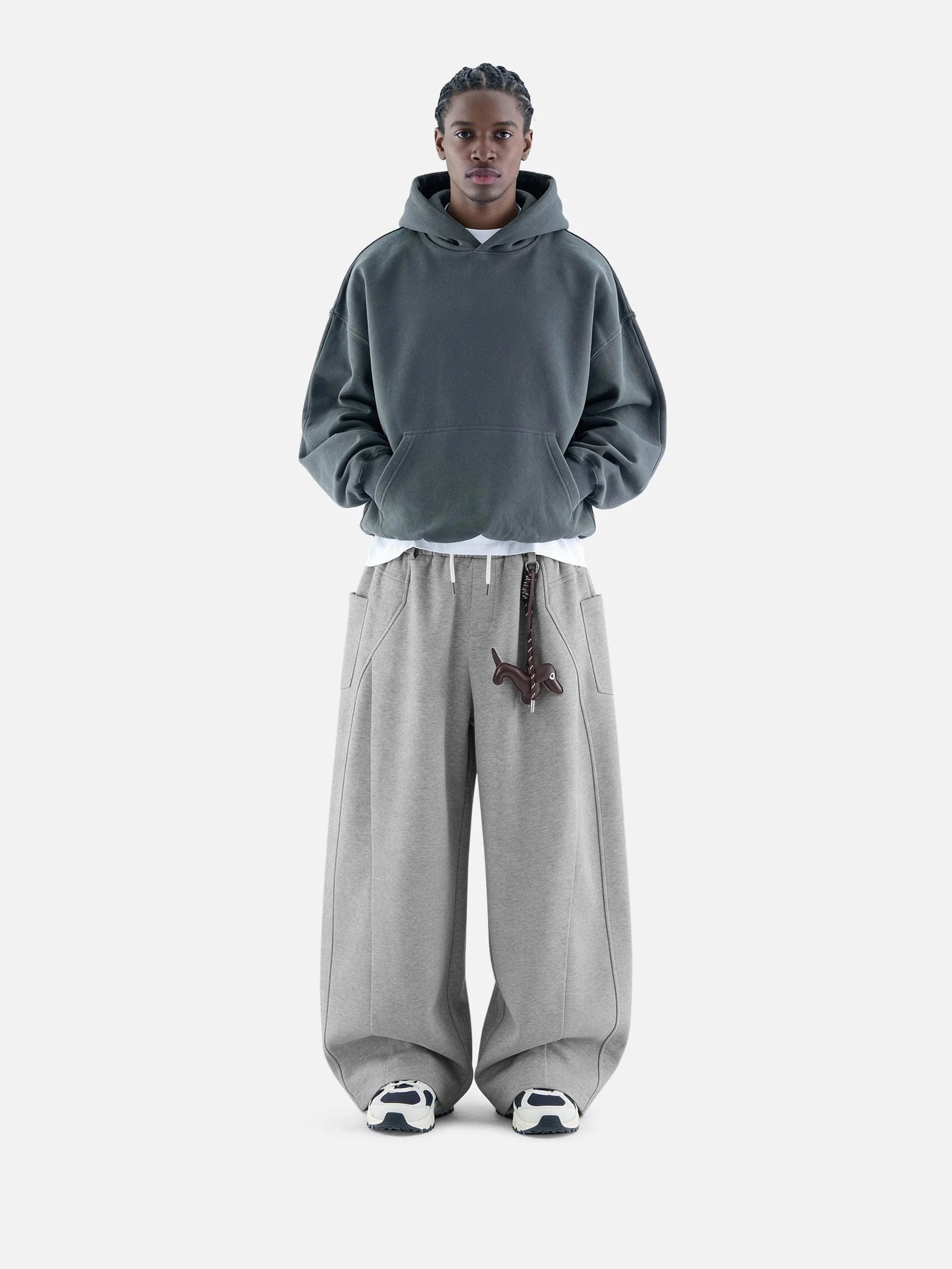 Person wearing a grey hoodie and pants on a white background