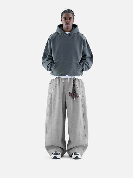 Person wearing a grey hoodie and pants on a white background