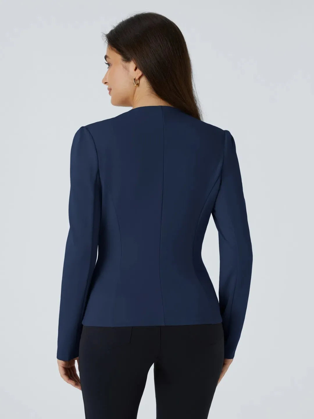 Woman wearing a blue buisness jacket with gold buttons on a light gray background