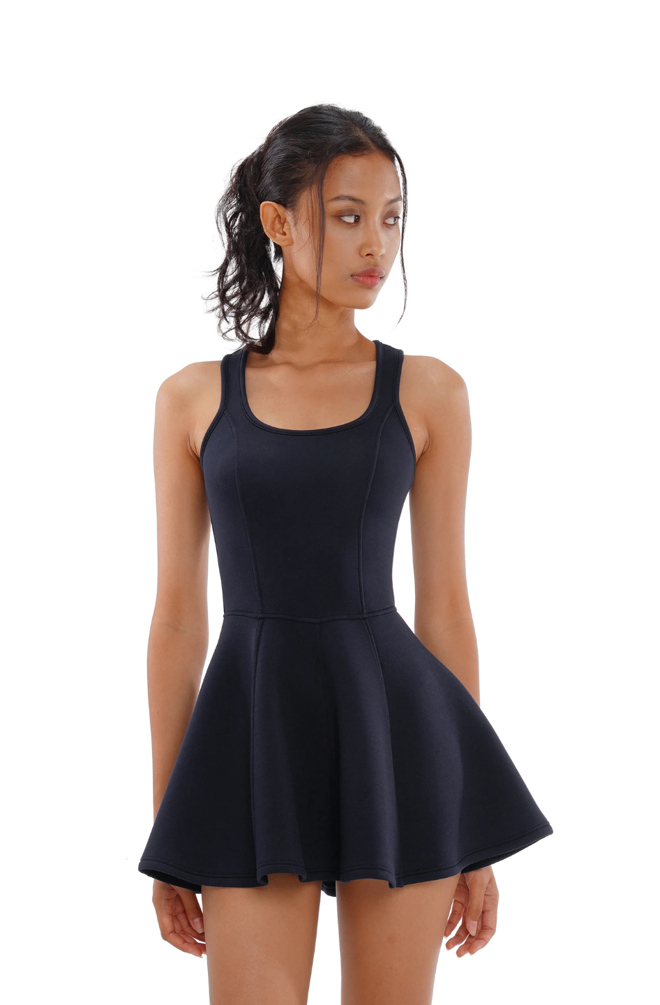 A woman wearing a navy blue sleeveless tennis dress with a square neckline and pleated skirt.