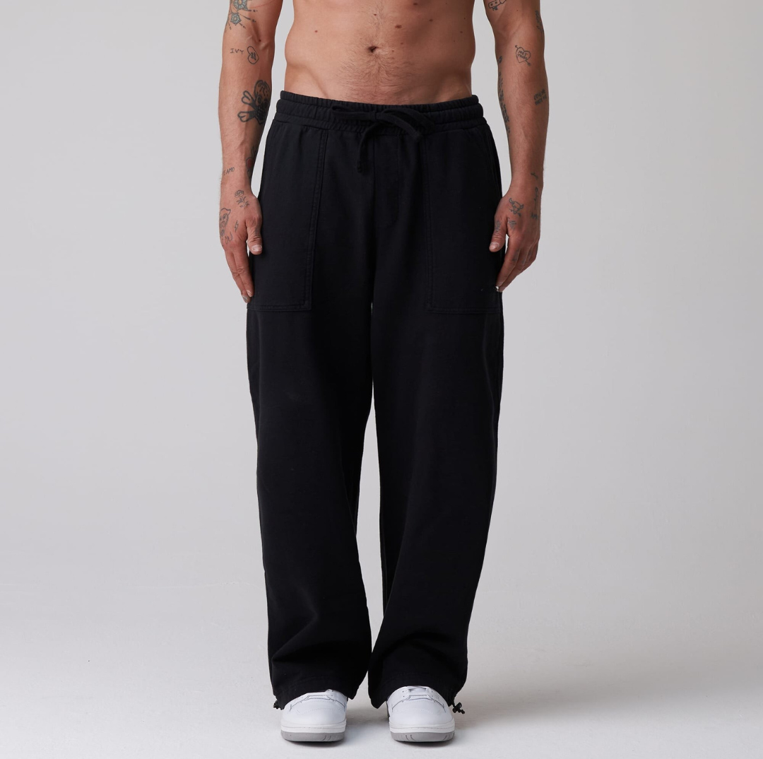 Black sweatpants worn by a person on a gray background