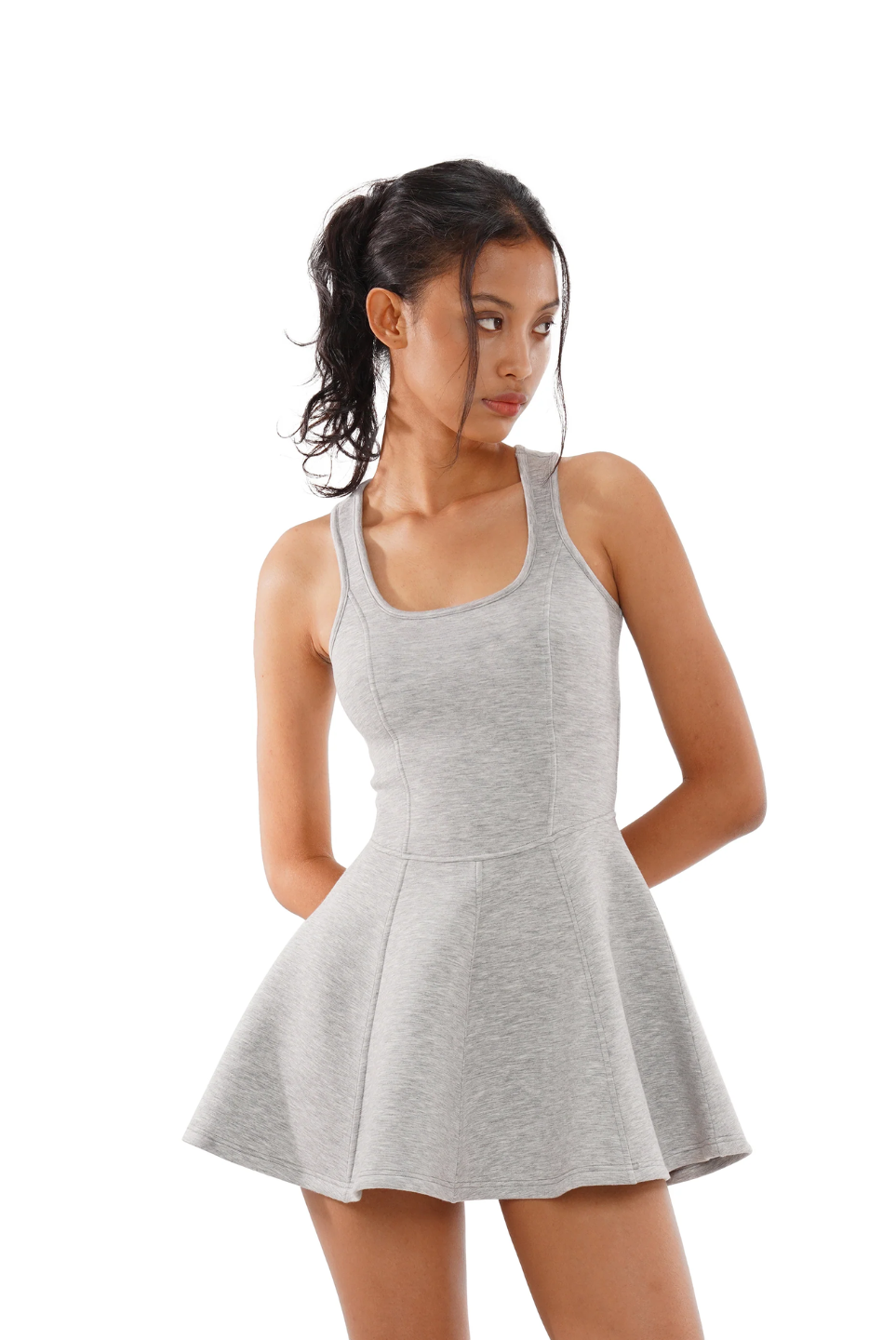 A woman wearing a grey sleeveless tennis dress with a square neckline and pleated skirt.