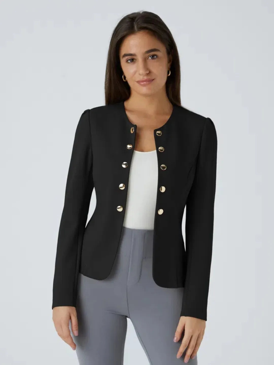 Woman wearing a black buisness jacket with gold buttons on a light gray background