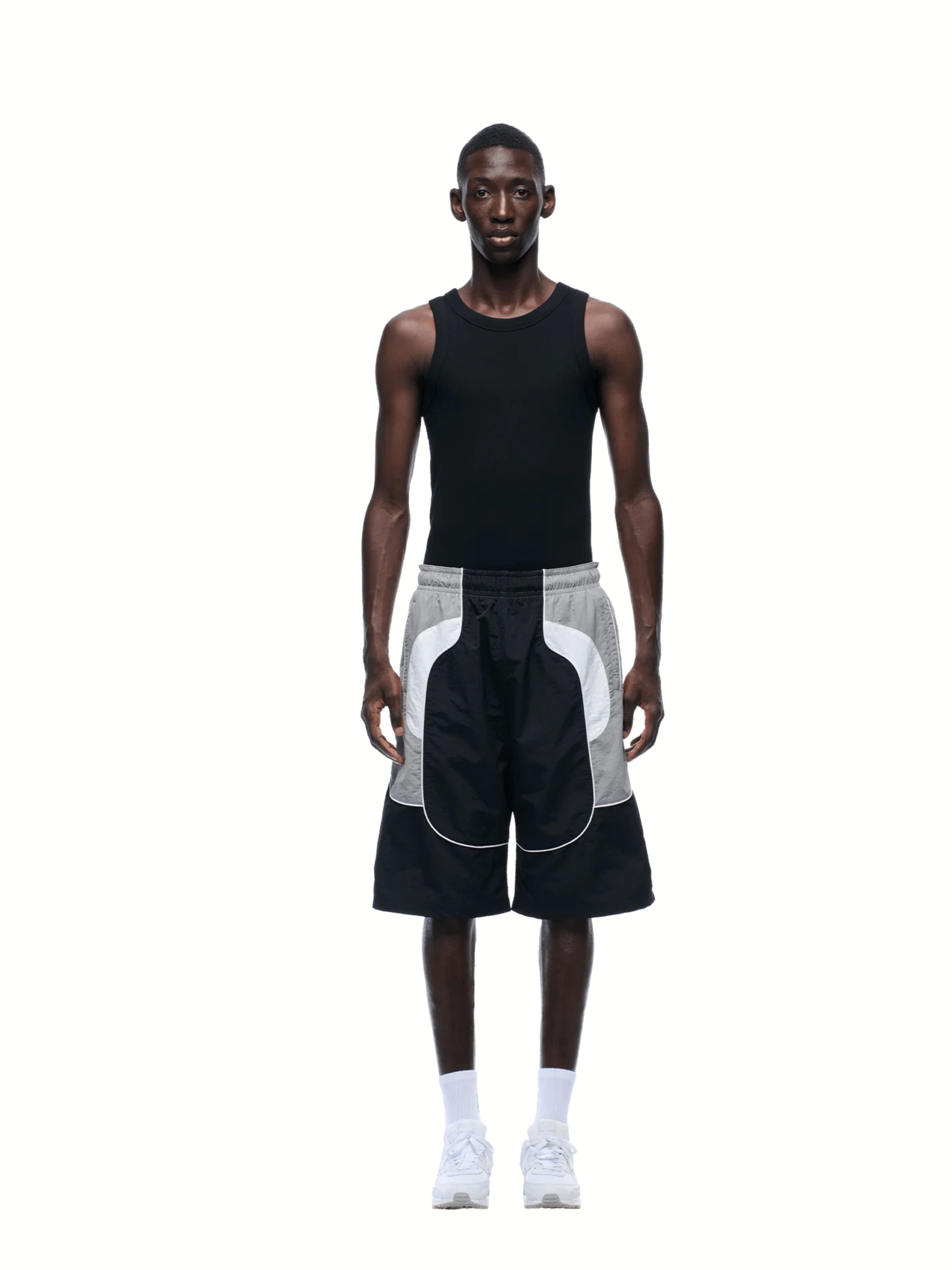 Man wearing a black sleeveless shirt and black and white shorts on a white background