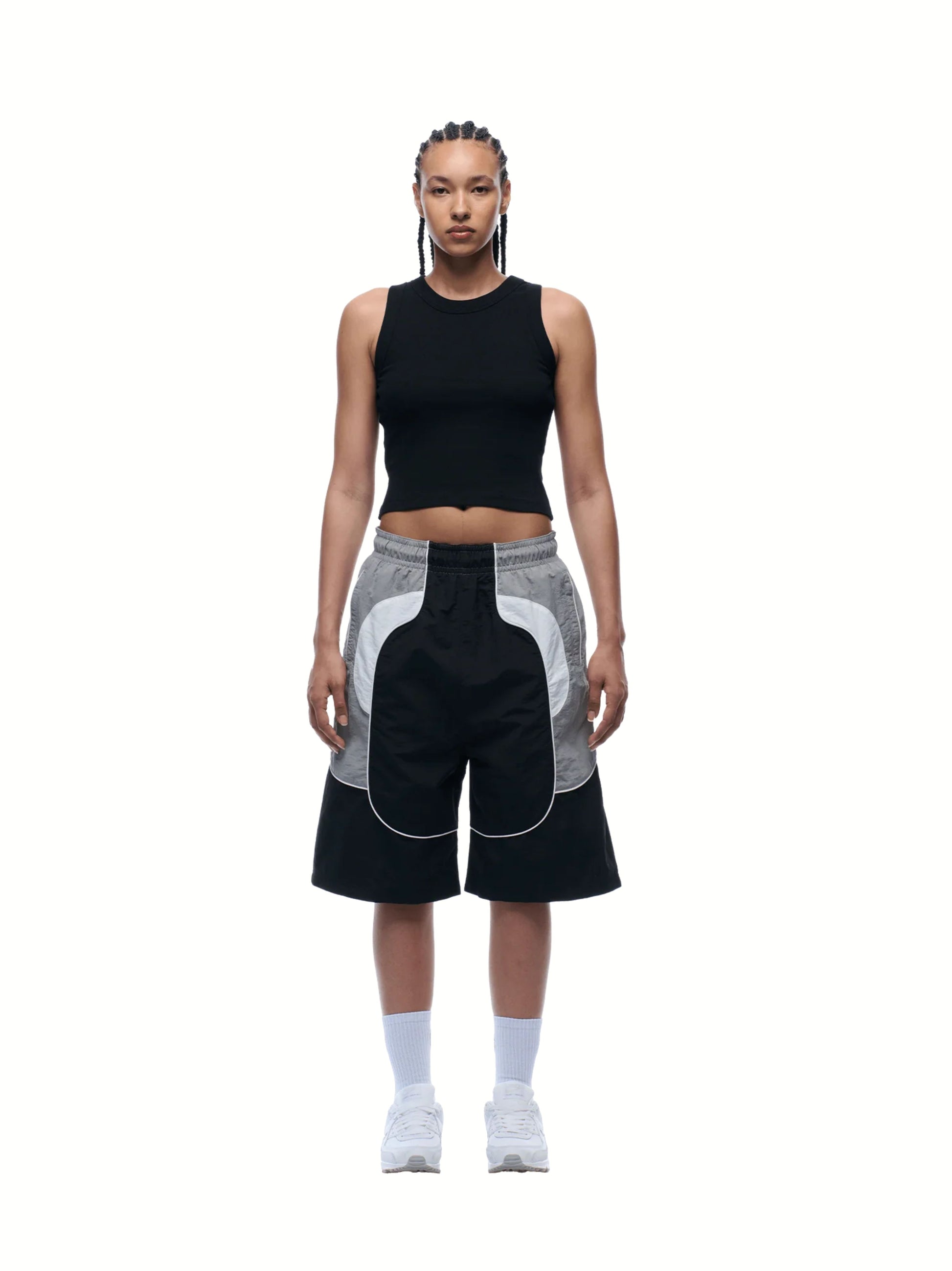 Person wearing a black sleeveless top and black and gray shorts on a white background