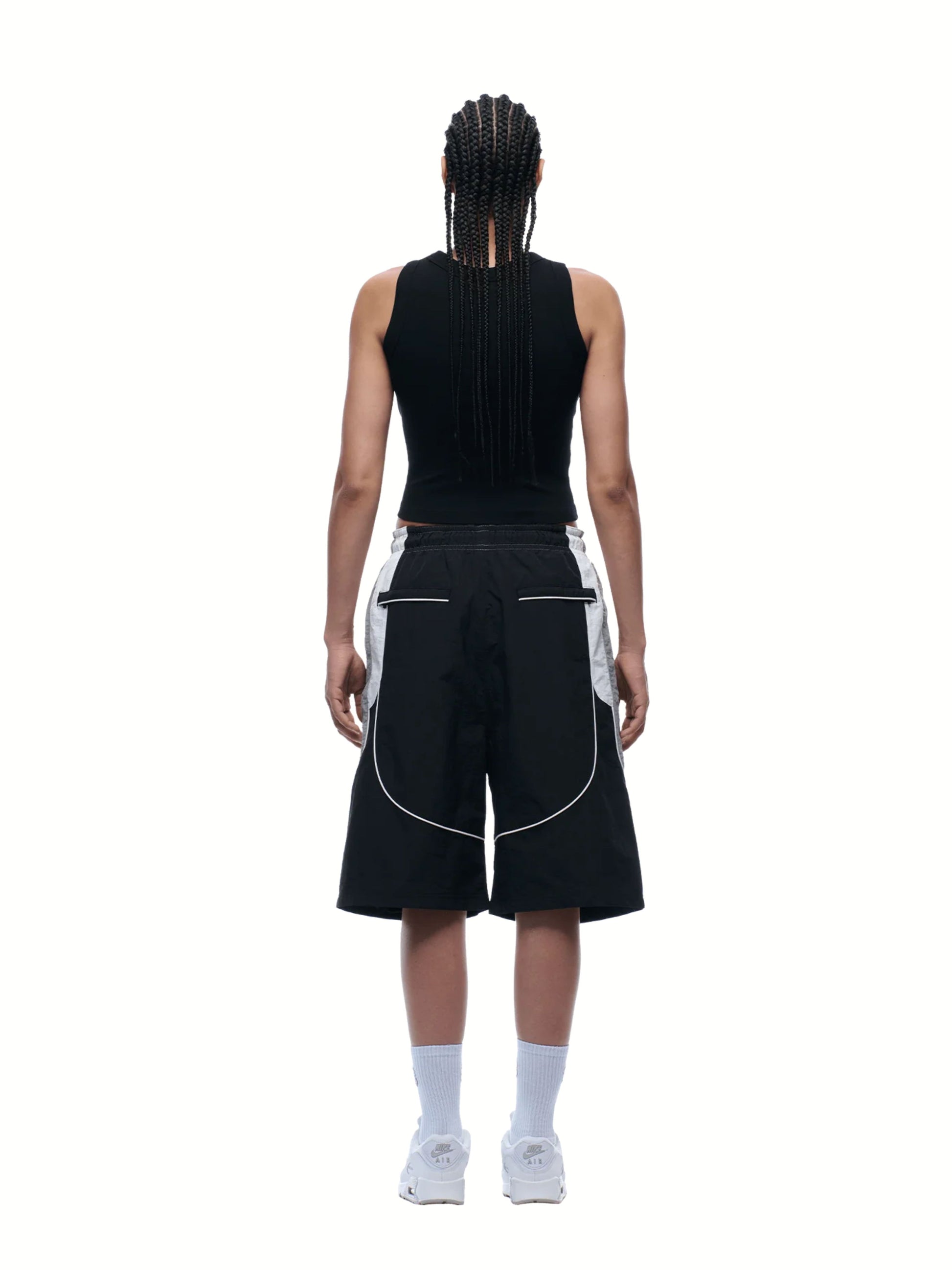Person wearing a black sleeveless top and shorts with white accents on a white background