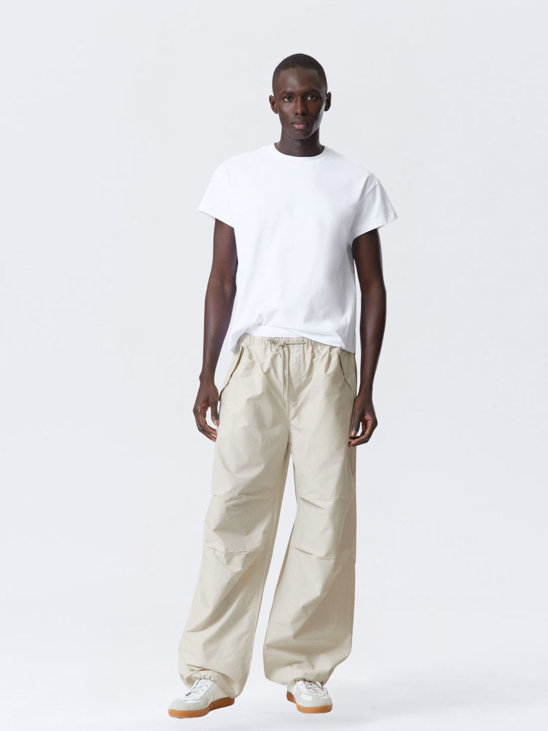 Person wearing a white t-shirt and beige pants on a white background