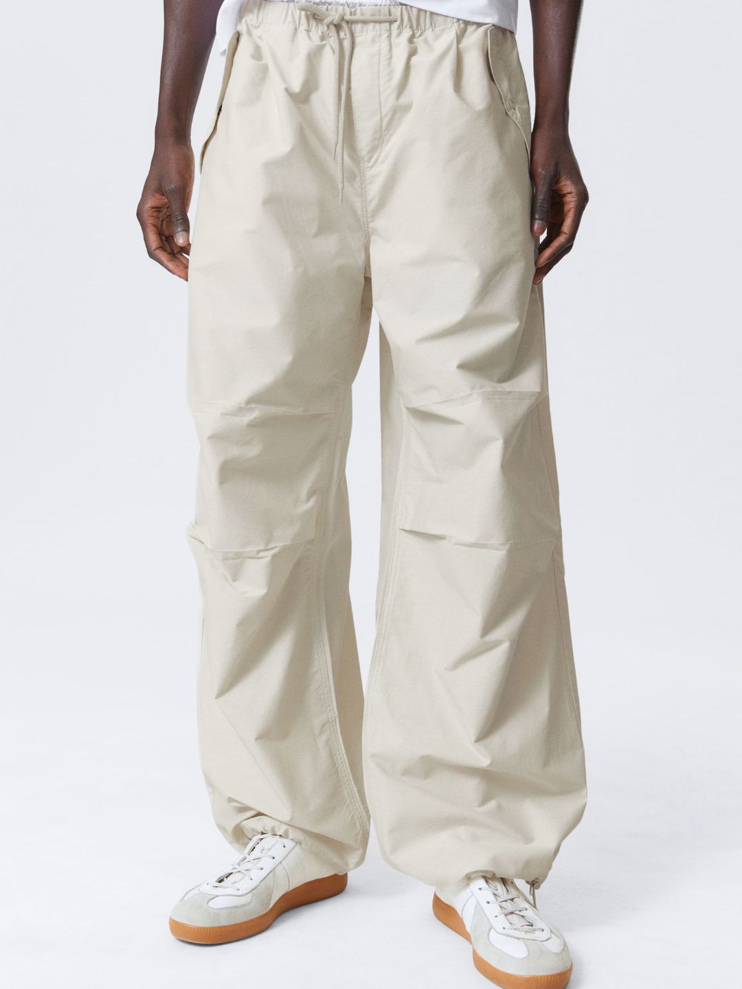 Beige pants worn by a person on a white background