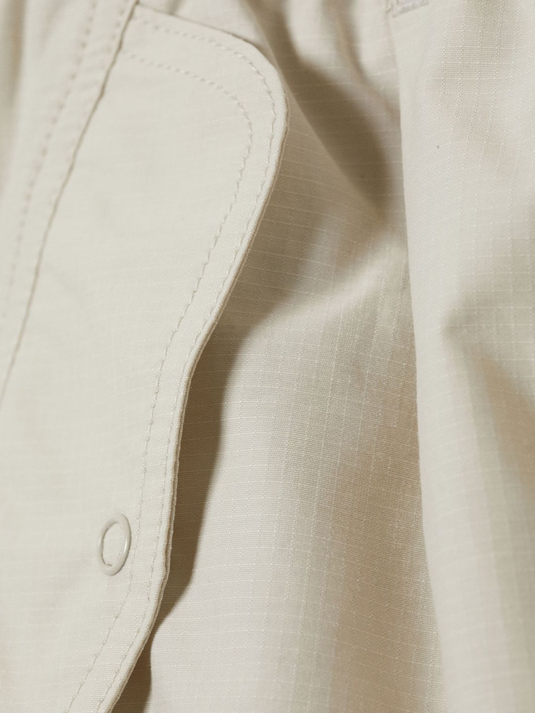 Close-up of a beige jacket with a button detail