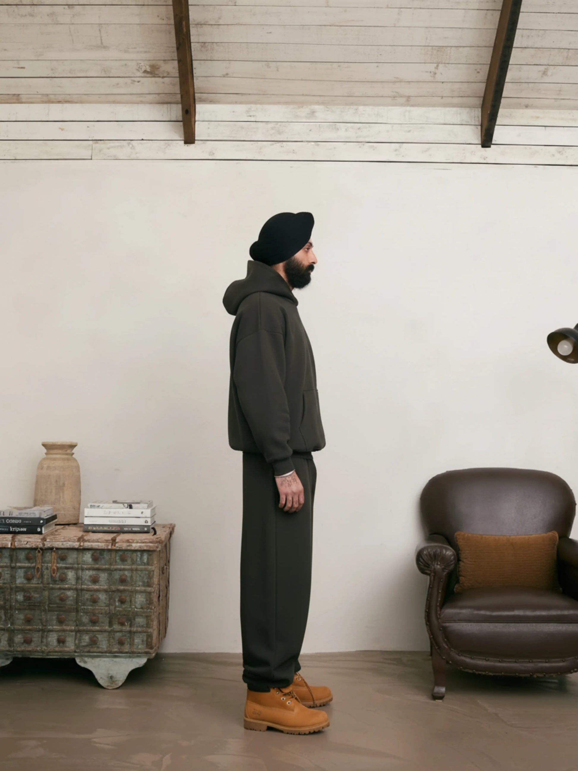 Person standing in a room with a white wall and wooden floor.