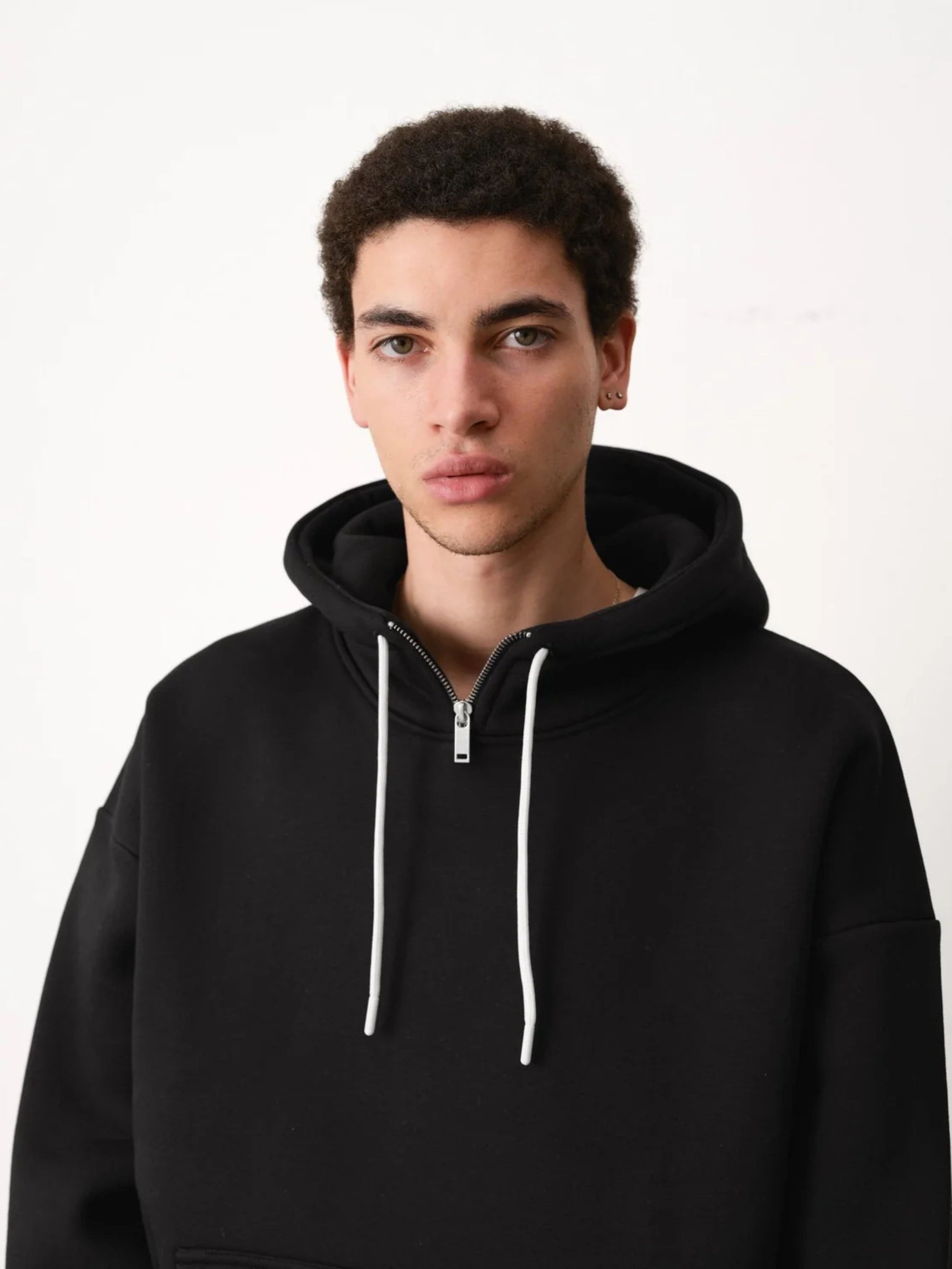 Person wearing a black hoodie with white drawstrings on a white background