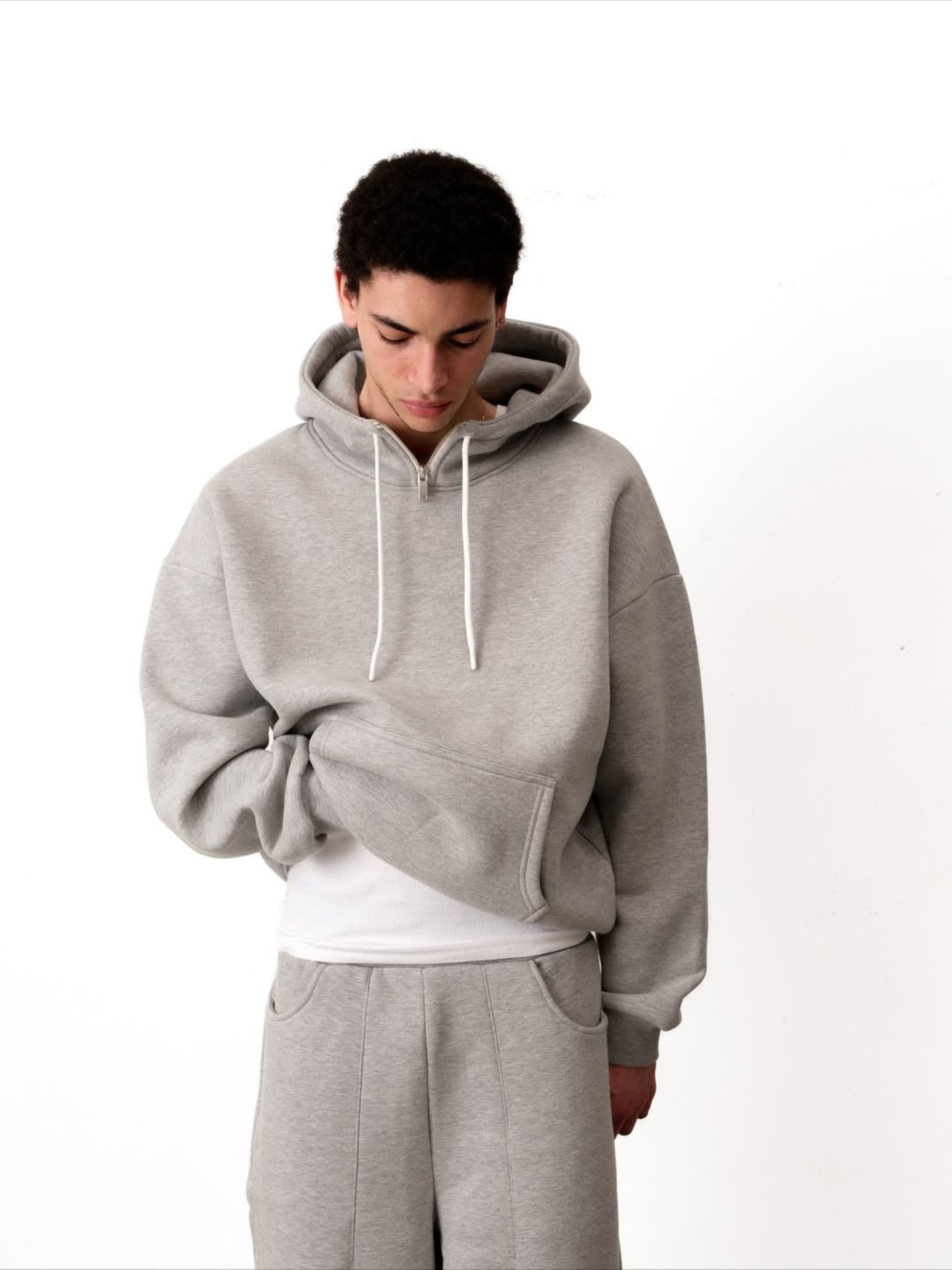Person wearing a gray hoodie and pants on a white background