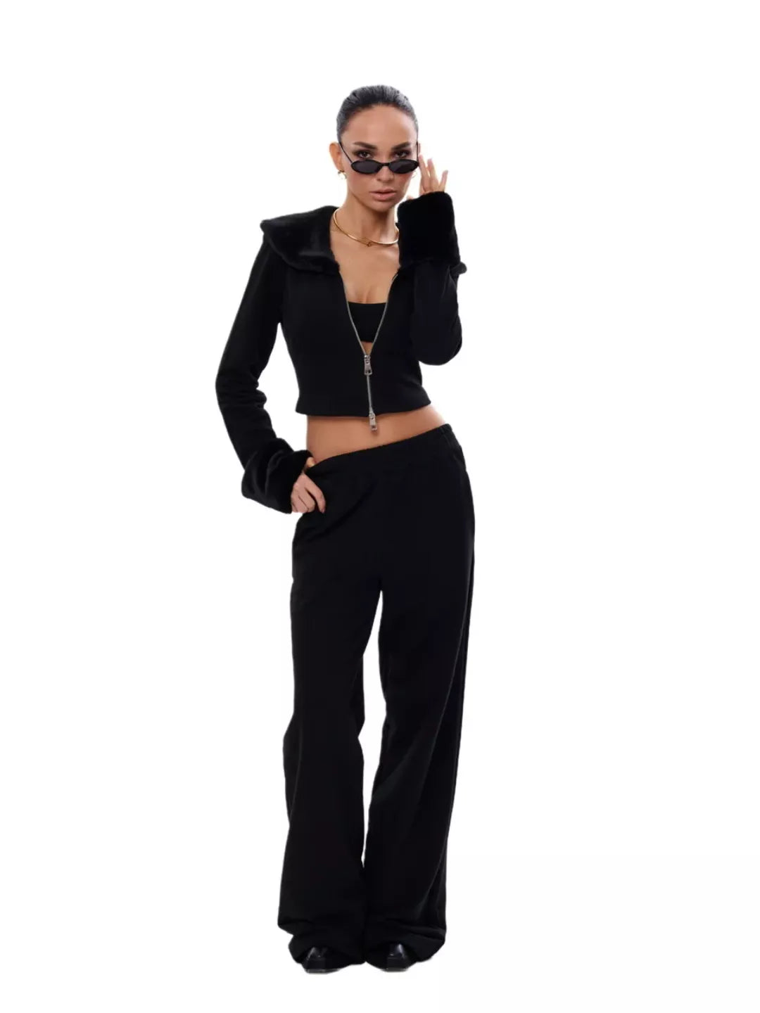 Woman wearing a black outfit with a jacket and pants on a white background