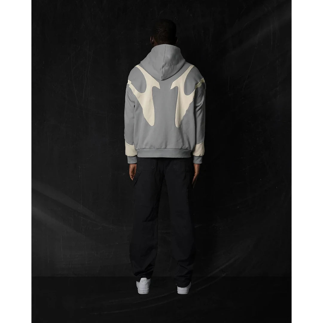 Person wearing a gray hoodie with white designs on the back against a black background