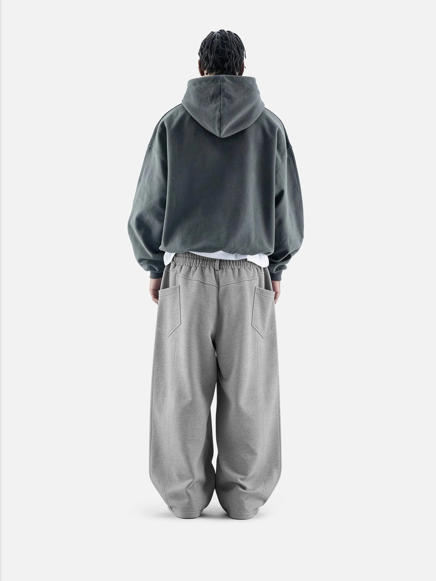 Person wearing a grey hoodie and pants on a white background