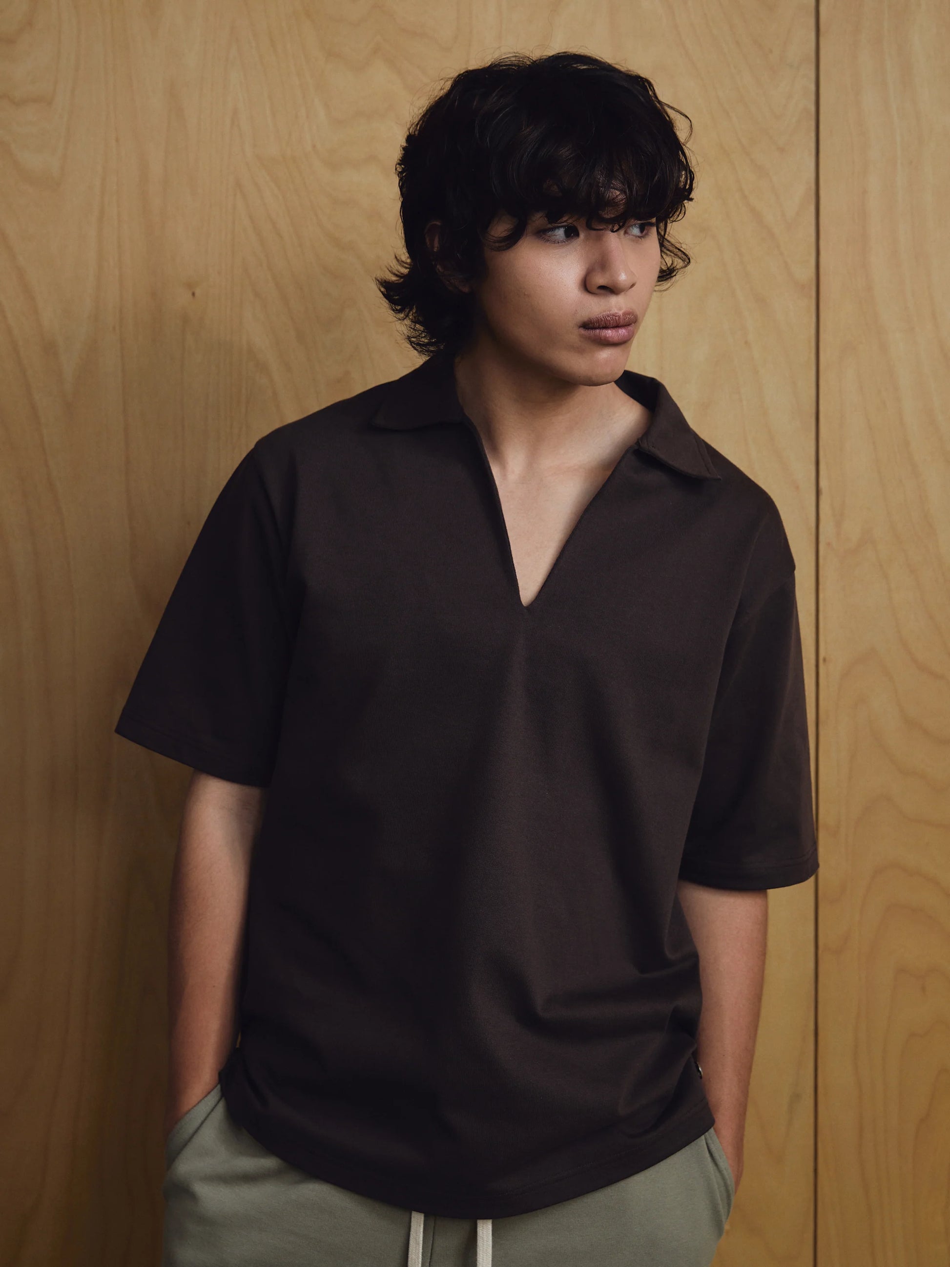 Person wearing a black polo shirt against a wooden background