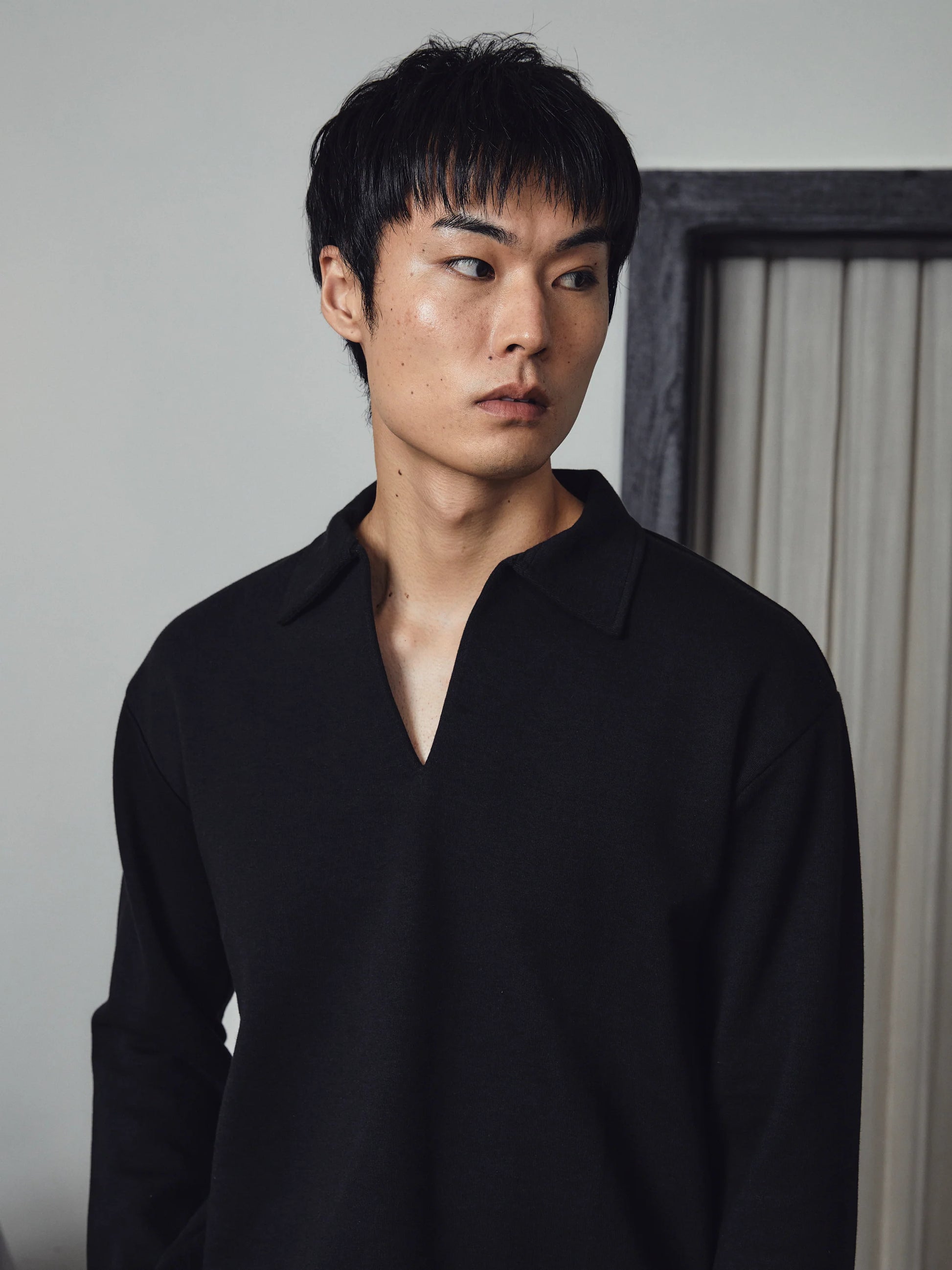 Man wearing a black shirt against a neutral background