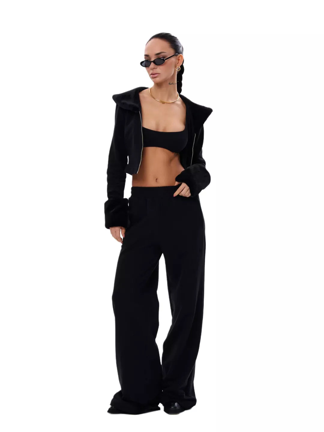 Person wearing a black outfit with sunglasses on a white background