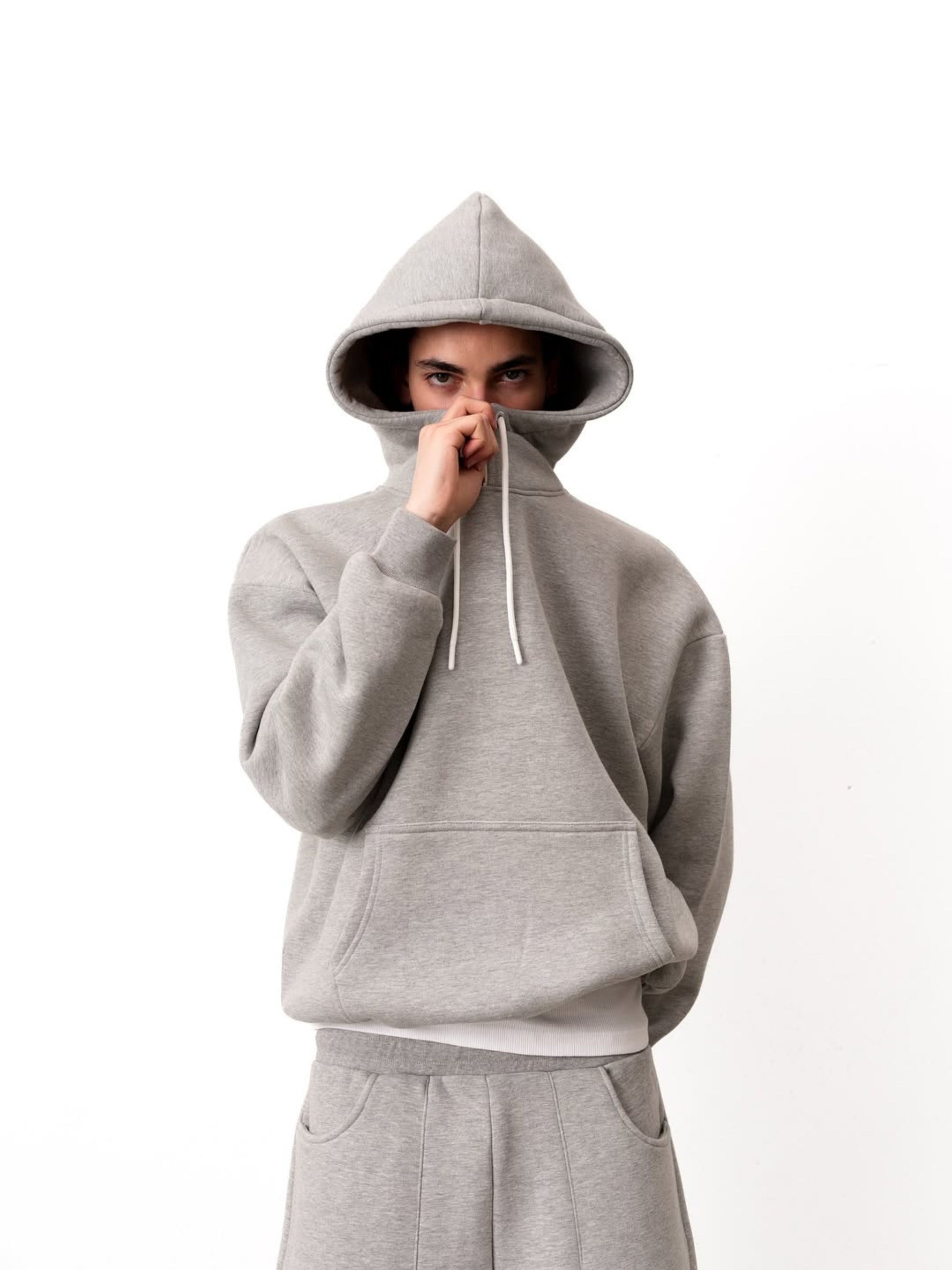 Person wearing a gray hoodie and pants on a white background