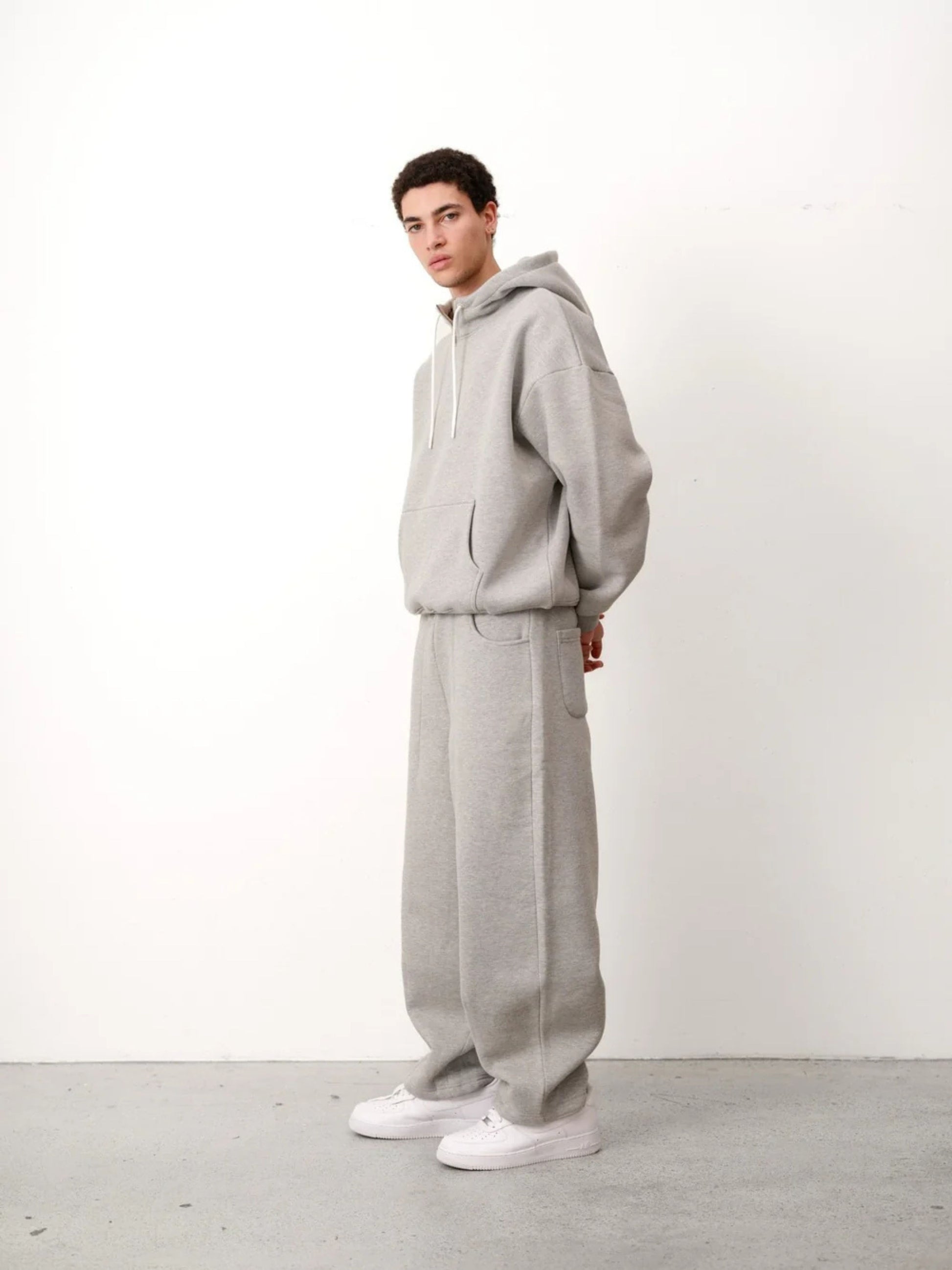 Person wearing a gray tracksuit against a white background