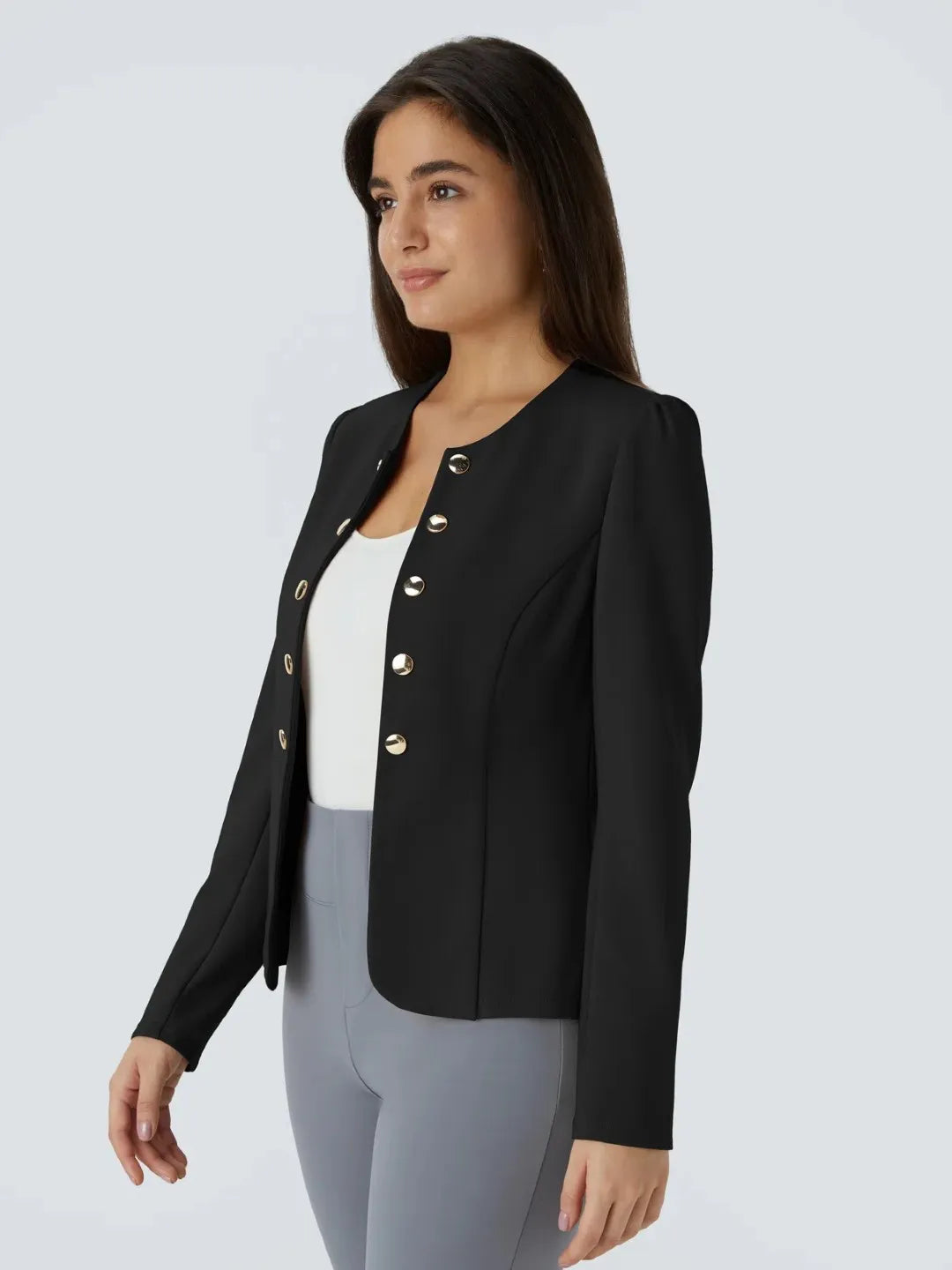 Woman wearing a black buisness jacket with gold buttons on a light gray background