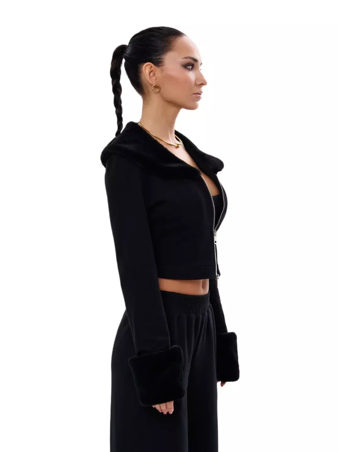 Woman wearing a black outfit with a cropped jacket and long skirt on a white background