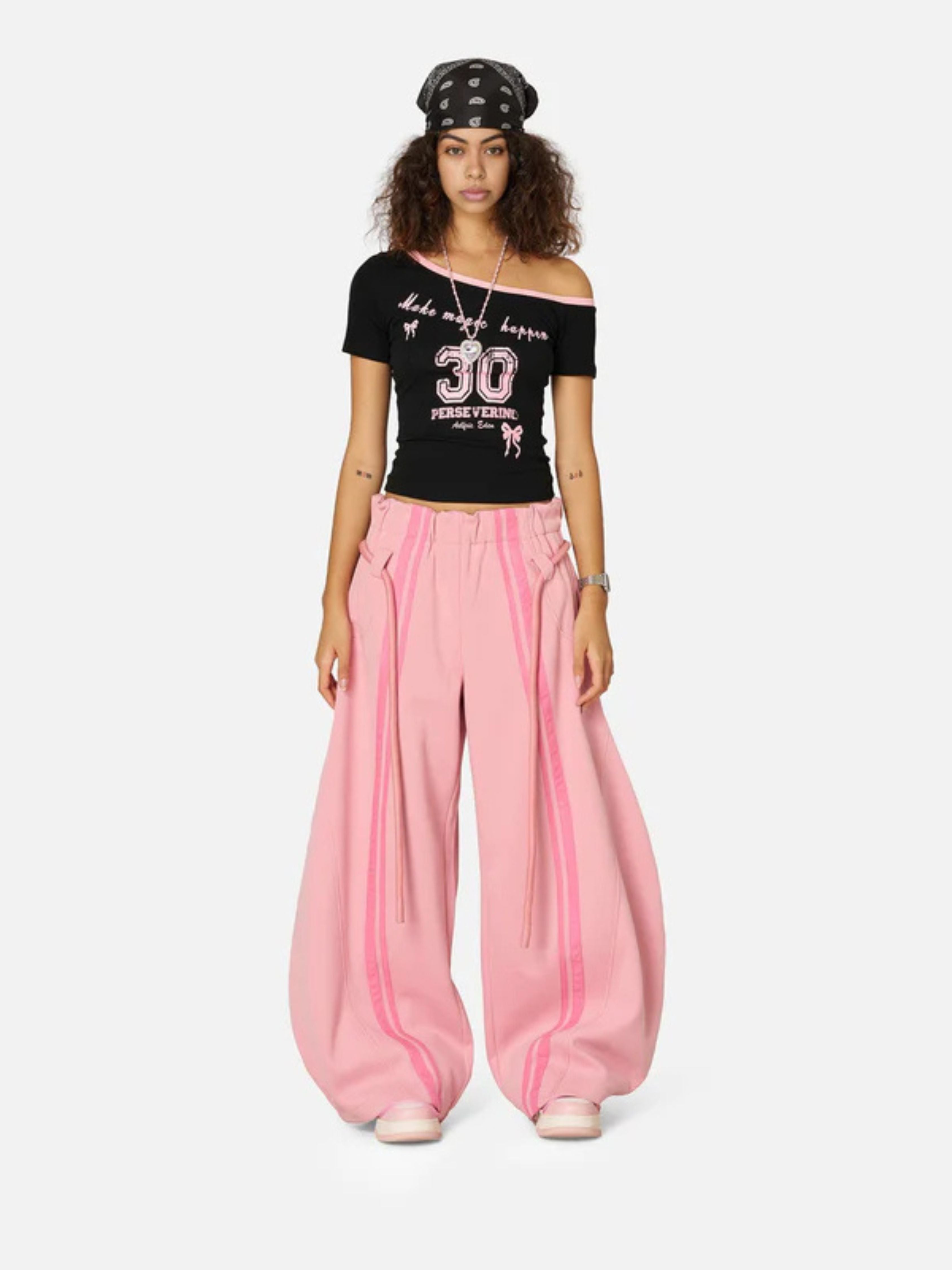 Woman wearing a black crop top with pink pants on a white background