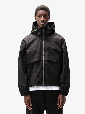 A person wearing a hooded Black jacket with a front zipper and an adjustable hood.