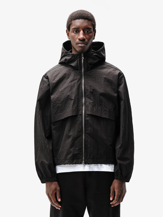 A person wearing a hooded Black jacket with a front zipper and an adjustable hood.