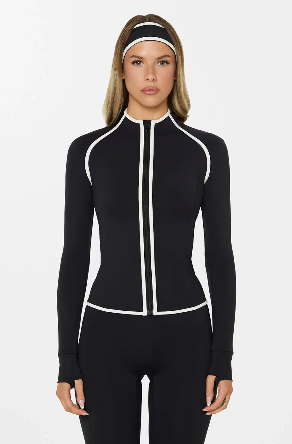 Woman wearing a black and white zip-up athletic outfit on a white background