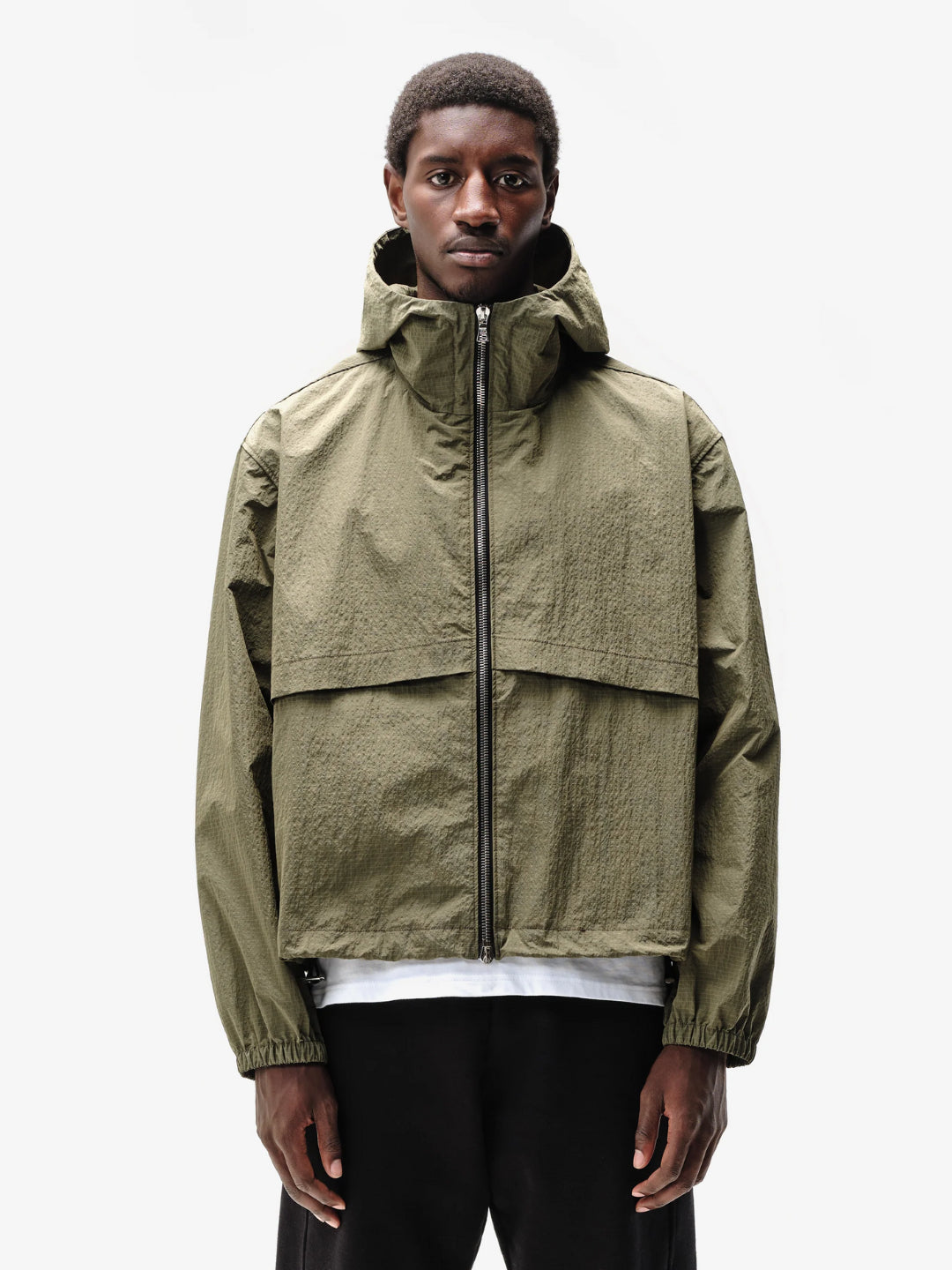 A person wearing a hooded green jacket with a front zipper and an adjustable hood.