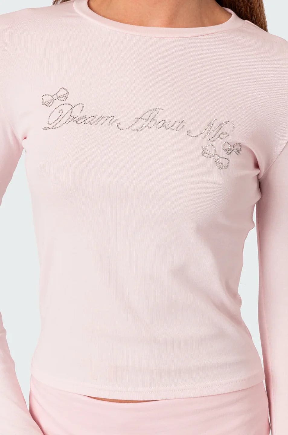 Pink long-sleeve top with 'Dream About Me' embroidery on a light gray background
