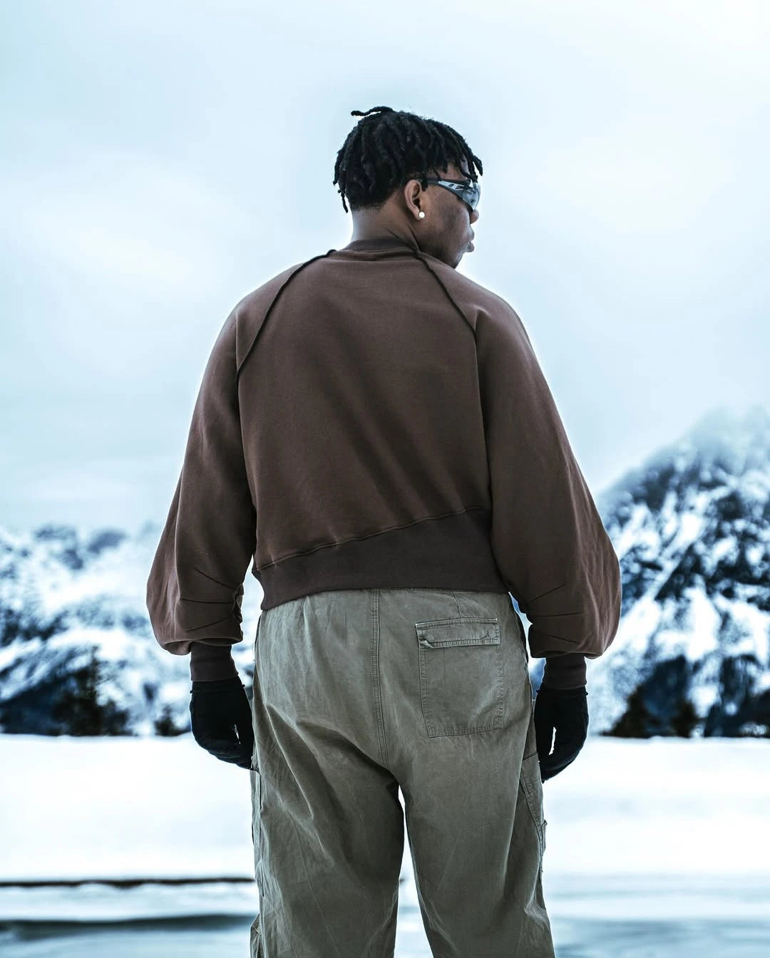 Person wearing a brown jacket and beige pants standing in a snowy landscape