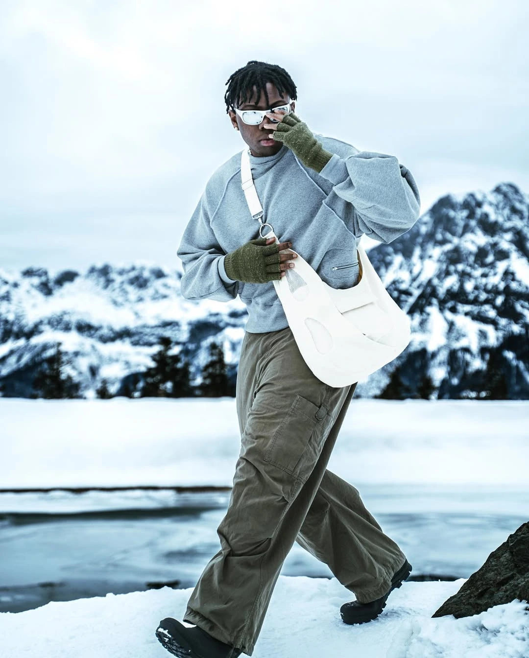 Person walking in a snowy landscape holding a white bag